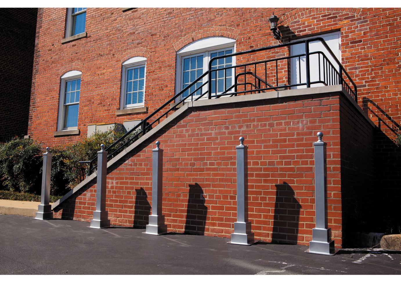 Charleston Series BollardPark silver steel bollards lining brick stairway with black metal railing, outdoor setting