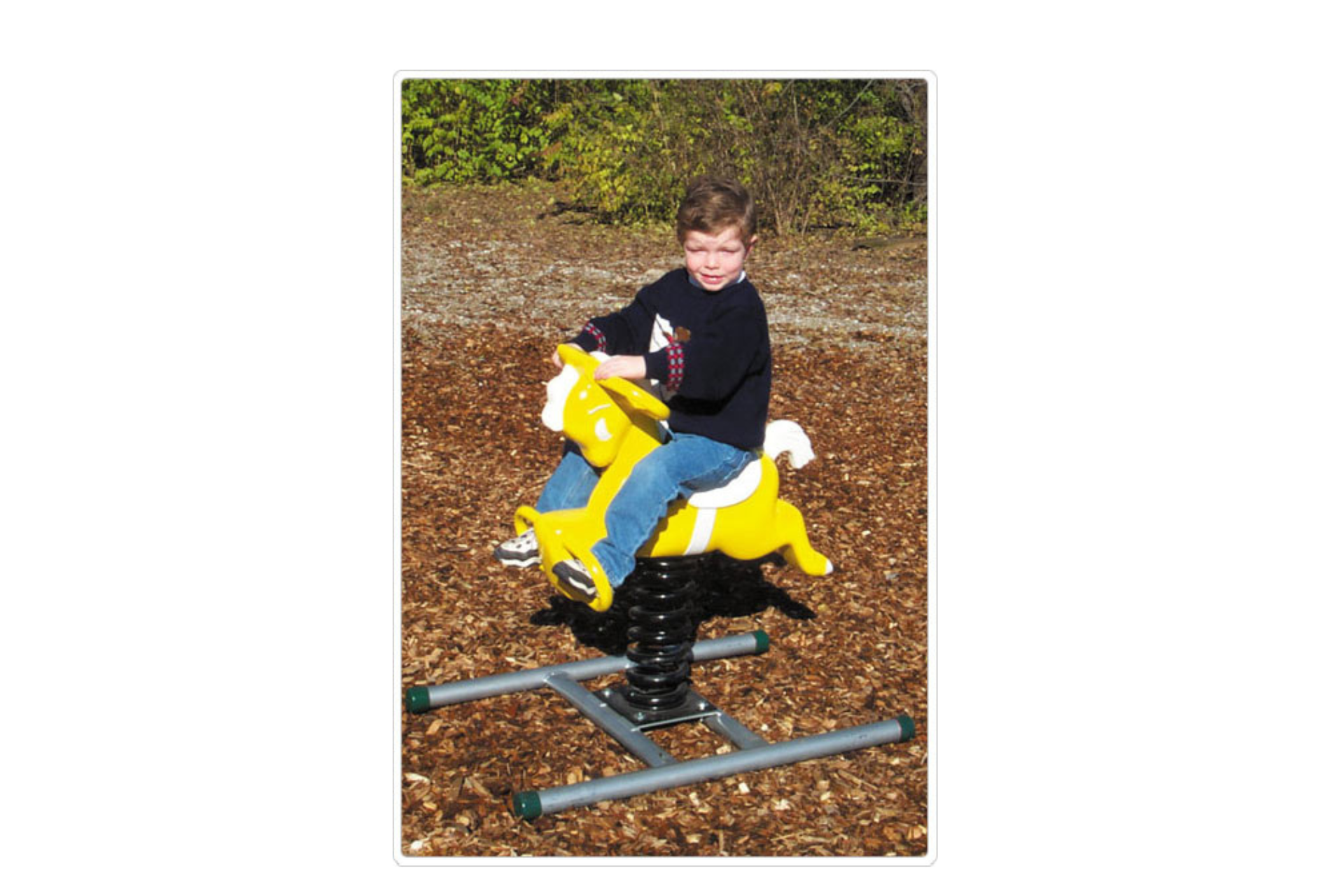 Spring Rider Portable Base supporting yellow horse spring rider on wood chip playground surface with child seated