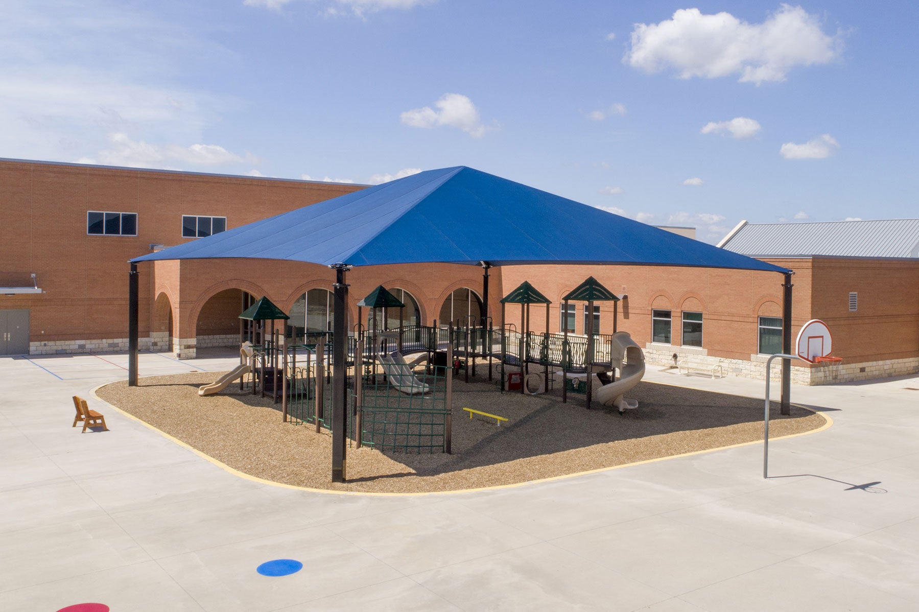 Hip Roof Shade Structure with 4 posts and blue fabric covering playground equipment and picnic area, UV-blocking playground shade