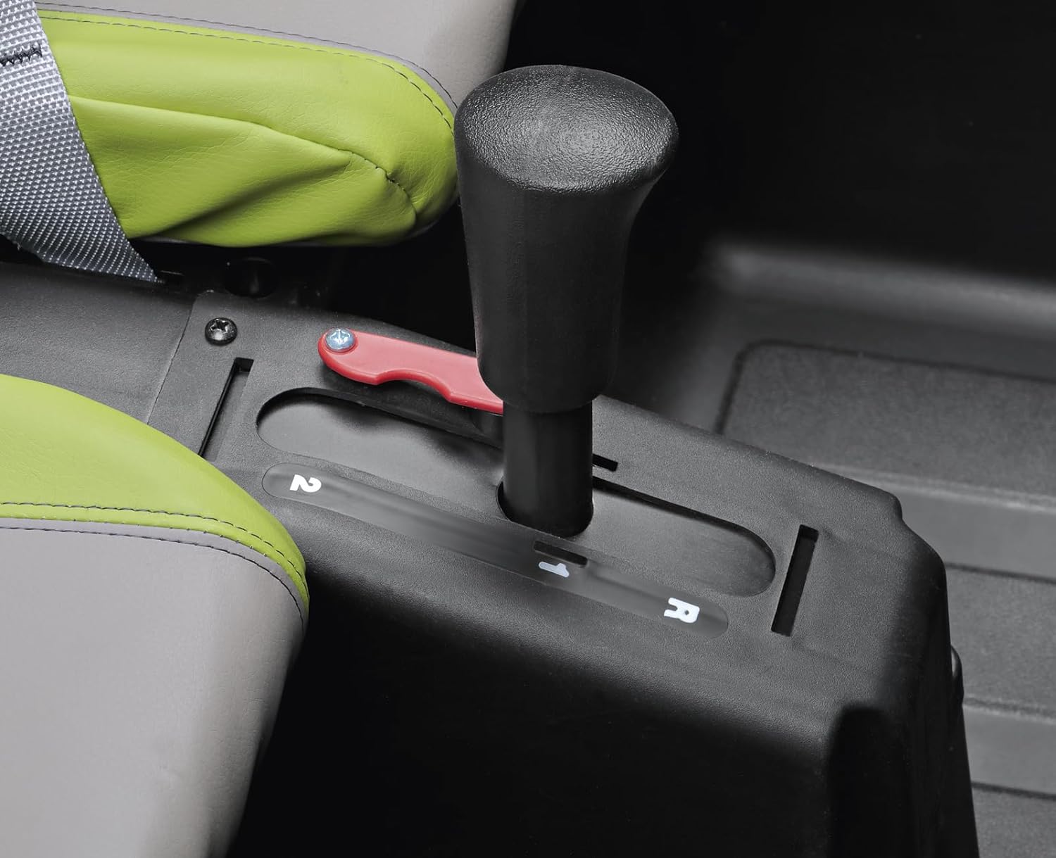 Close-up of green and gray ride-on vehicle seat with black gear shift lever and red safety lock on console