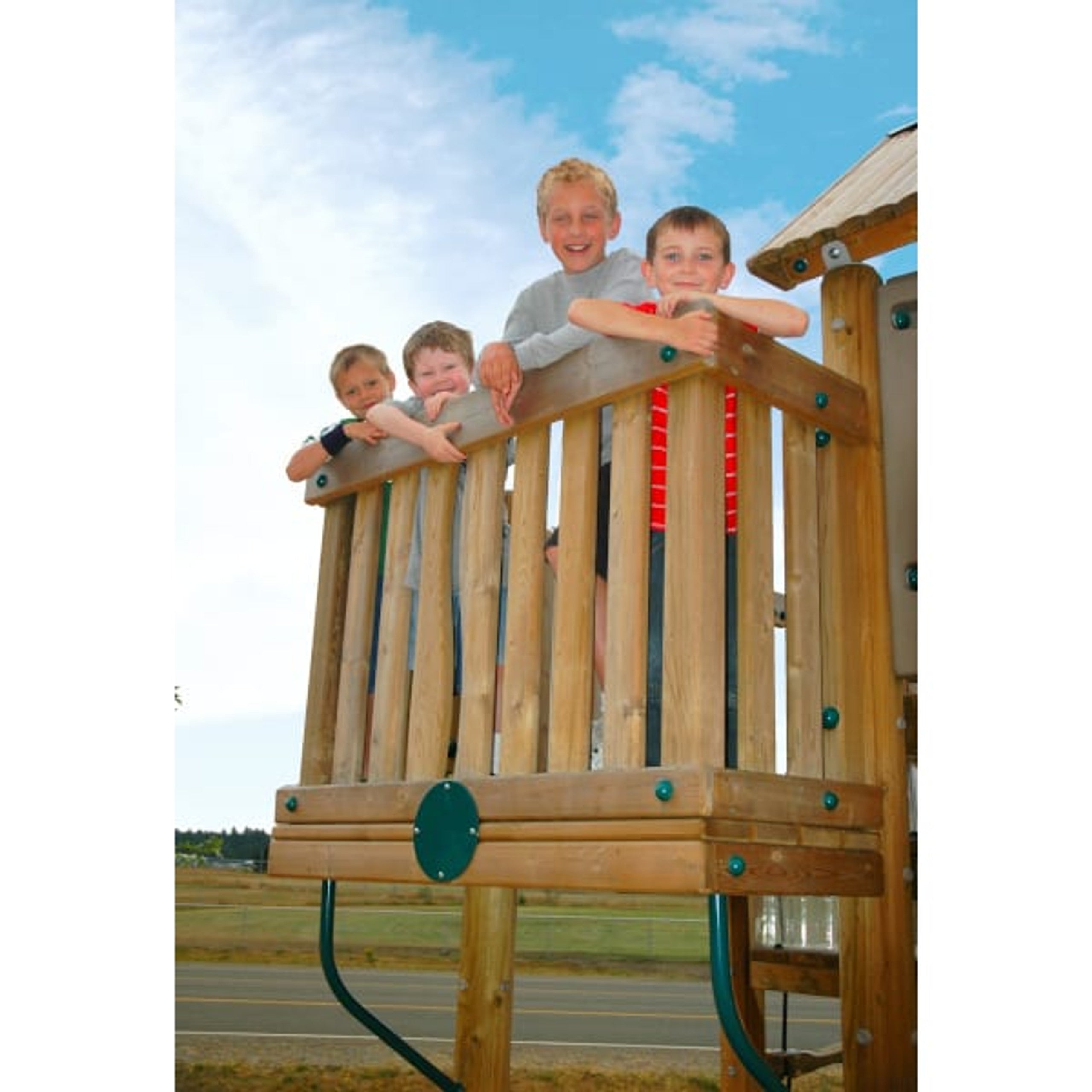 Four children leaning on wooden railing of elevated playground platform under blue sky, part of large ADA-accessible play system with climbing features