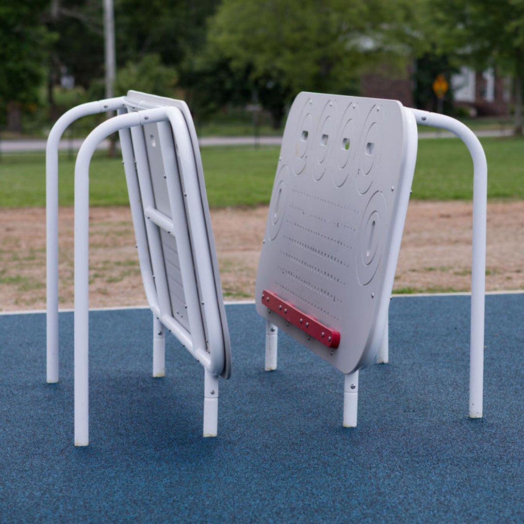 Two angled gray climbing walls with hand holds and white metal supports on blue safety surfacing for kids' outdoor fitness
