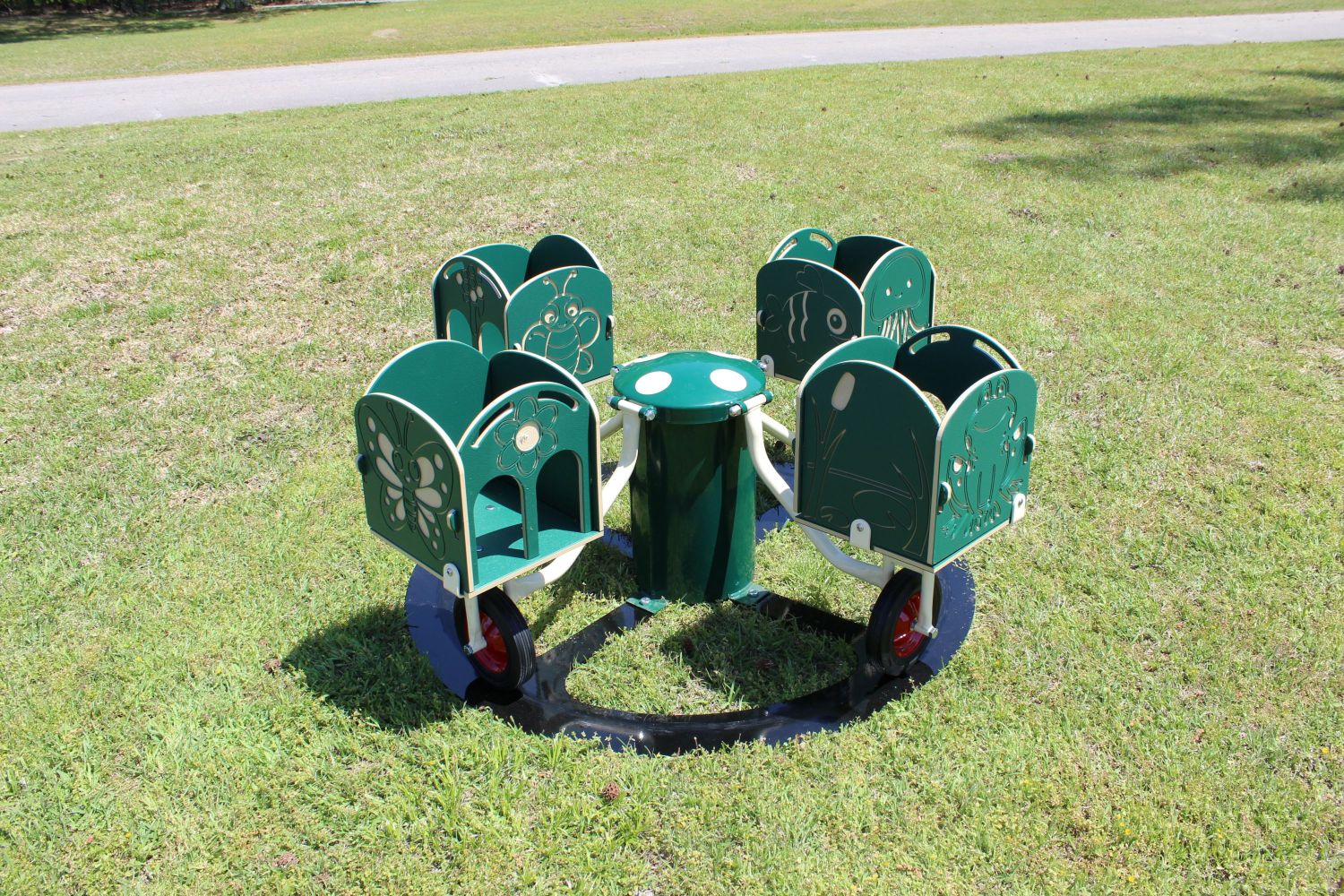 Four-seat green merry-go-round with animal and insect-shaped seats on grass in an outdoor playground
