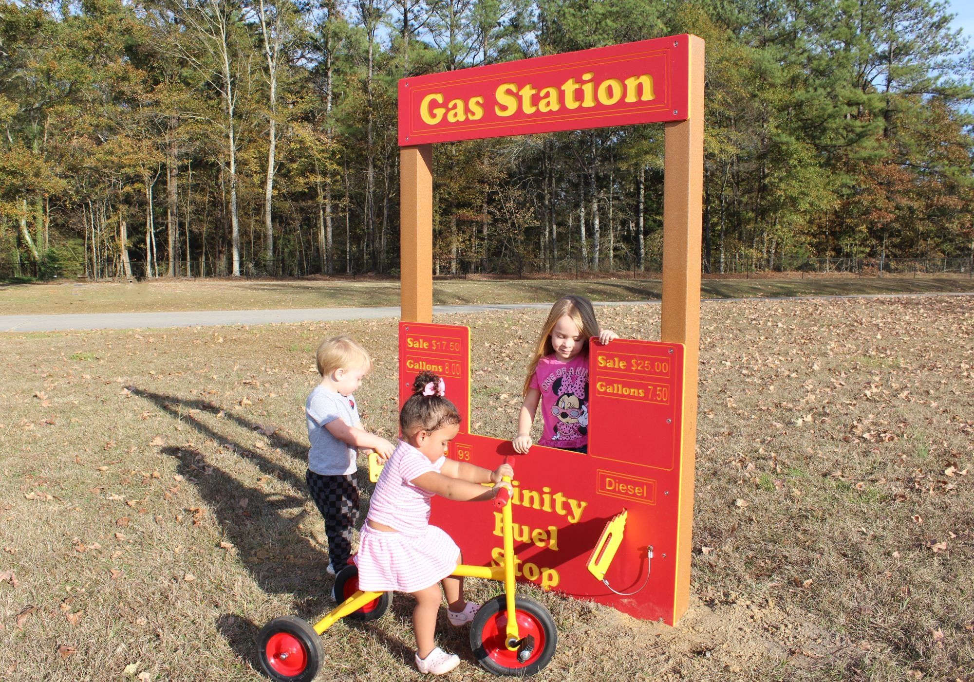 Infinity Gas Station playground equipment with red and yellow interactive pretend fuel pumps, tire spinner, and talk tube for inclusive imaginative play