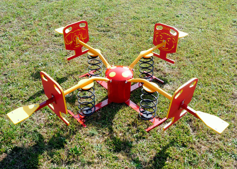 Four-person red and yellow spring rider with animal face panels on grassy outdoor playground