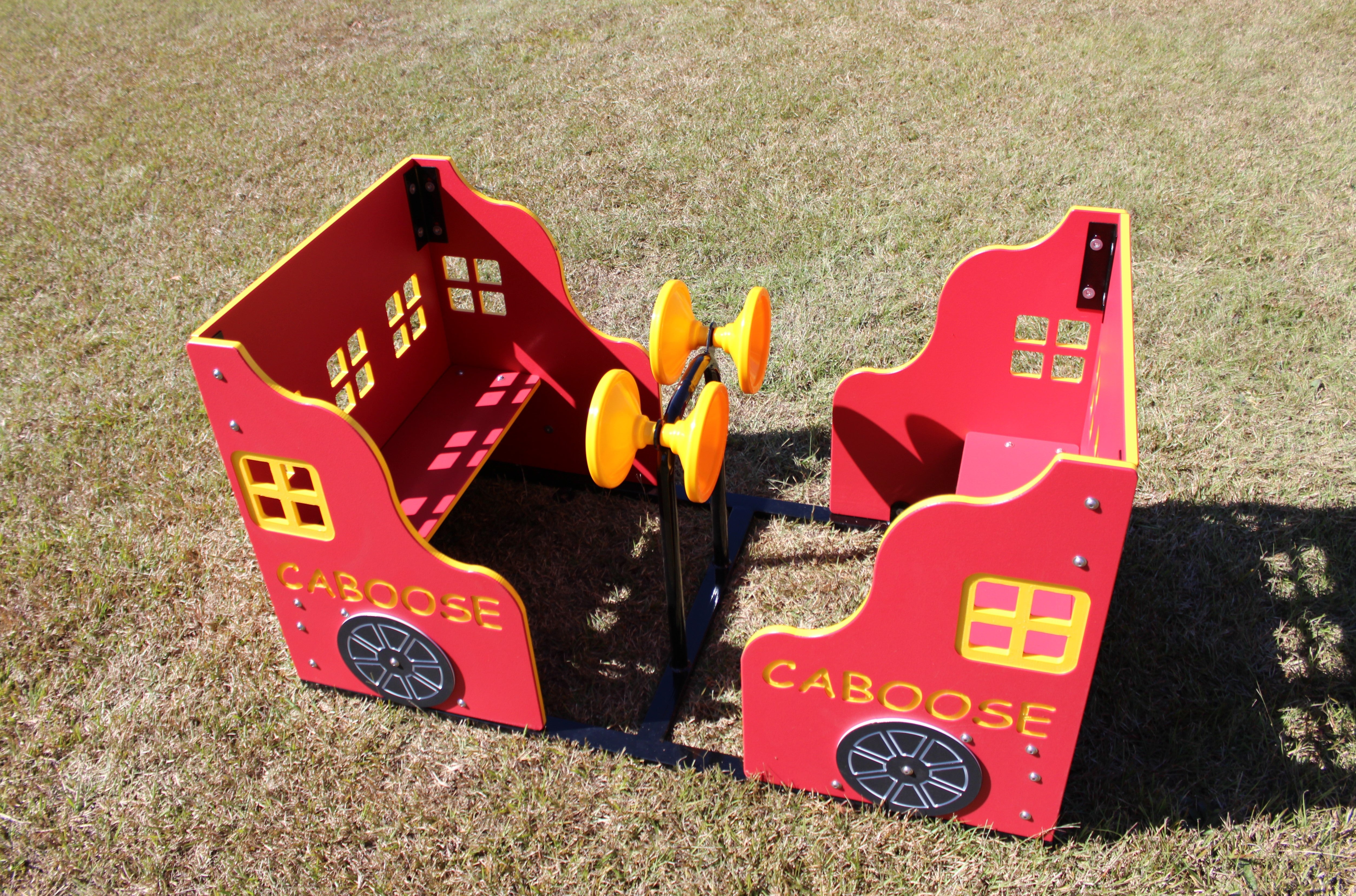 Red and yellow outdoor playground caboose with interactive yellow wheels on grass