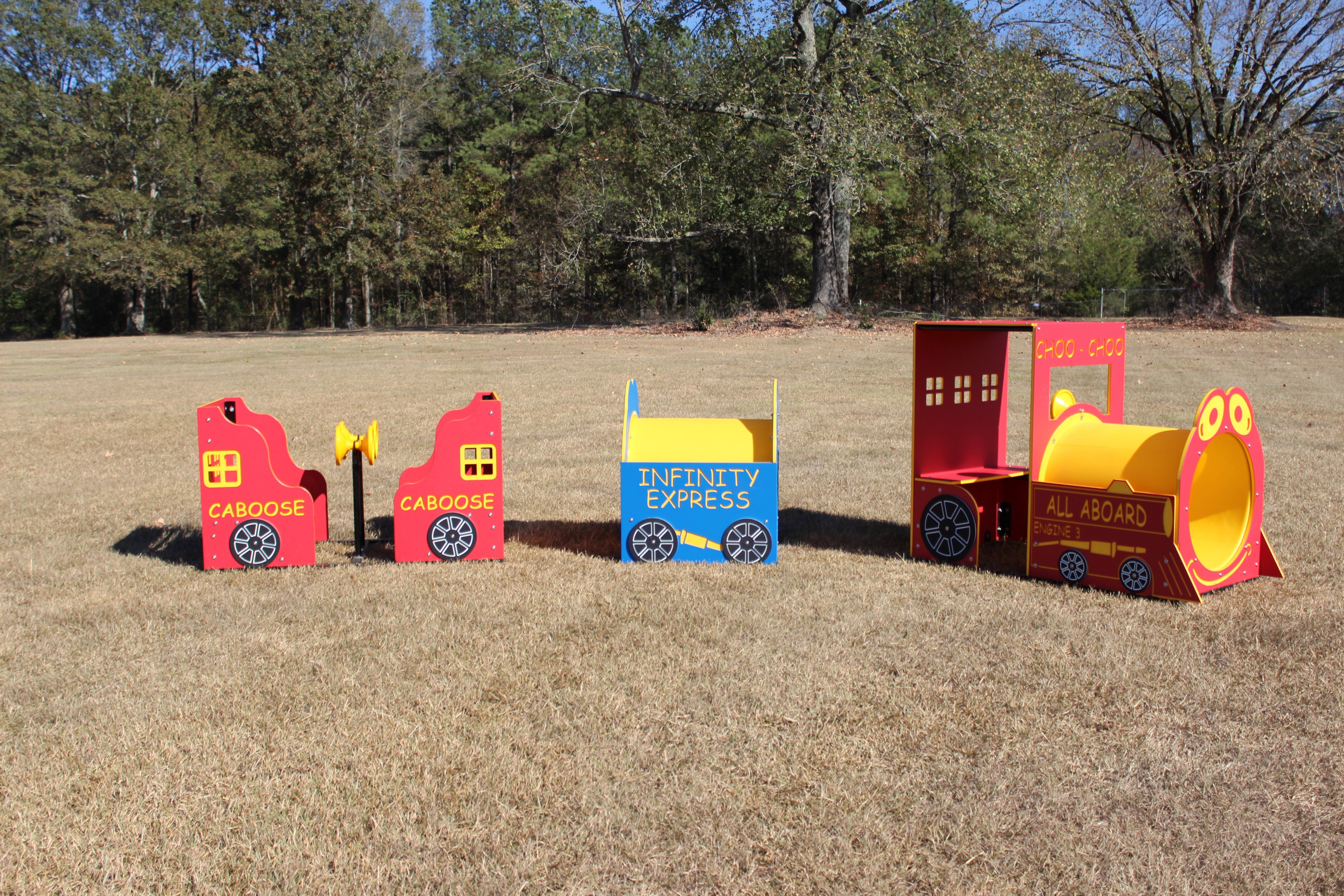 Colorful outdoor playground train set with red cabooses, blue middle car, and yellow-red engine on grass field