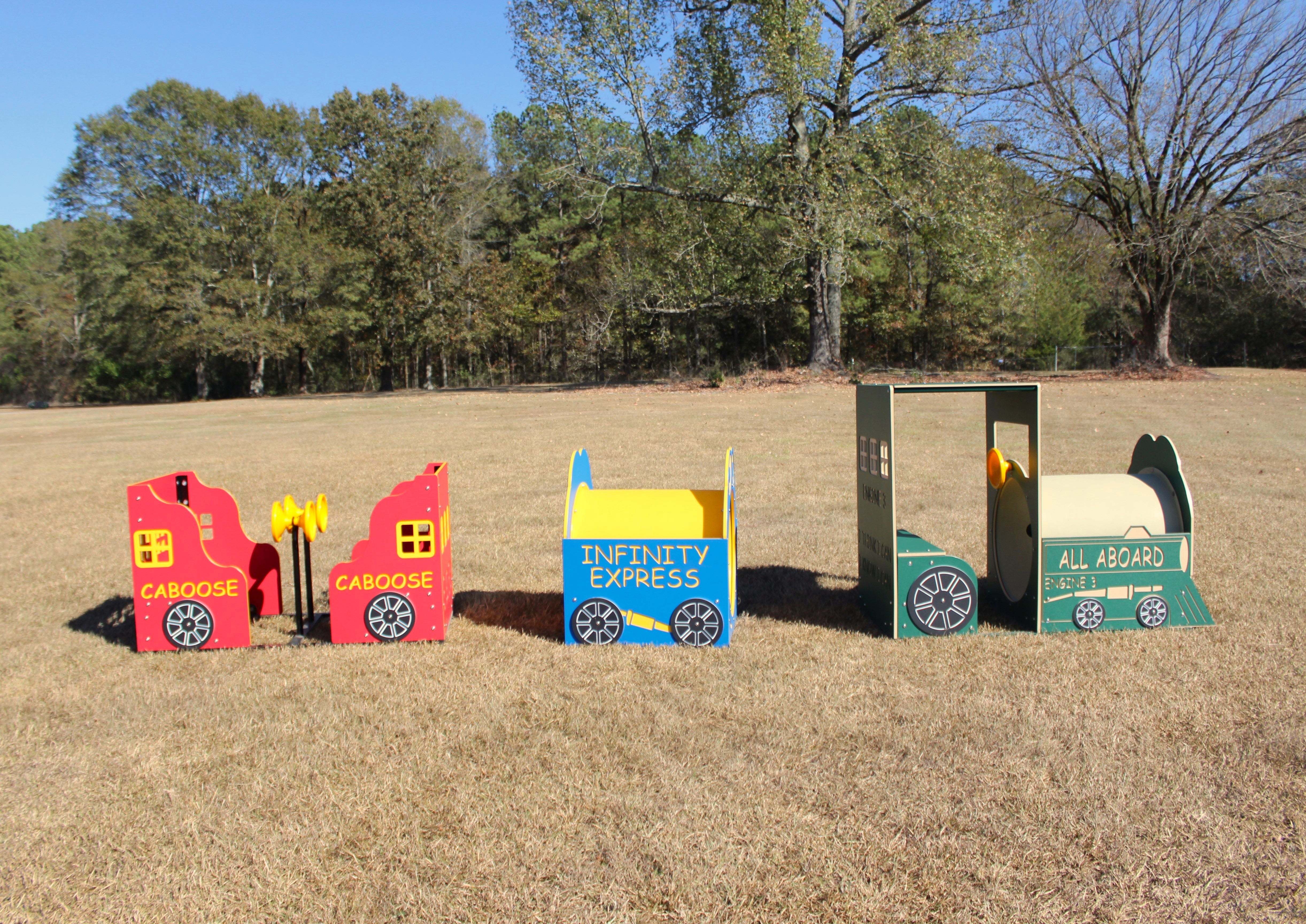 Colorful outdoor playground set with train-themed engine, caboose, and open car on grass field.