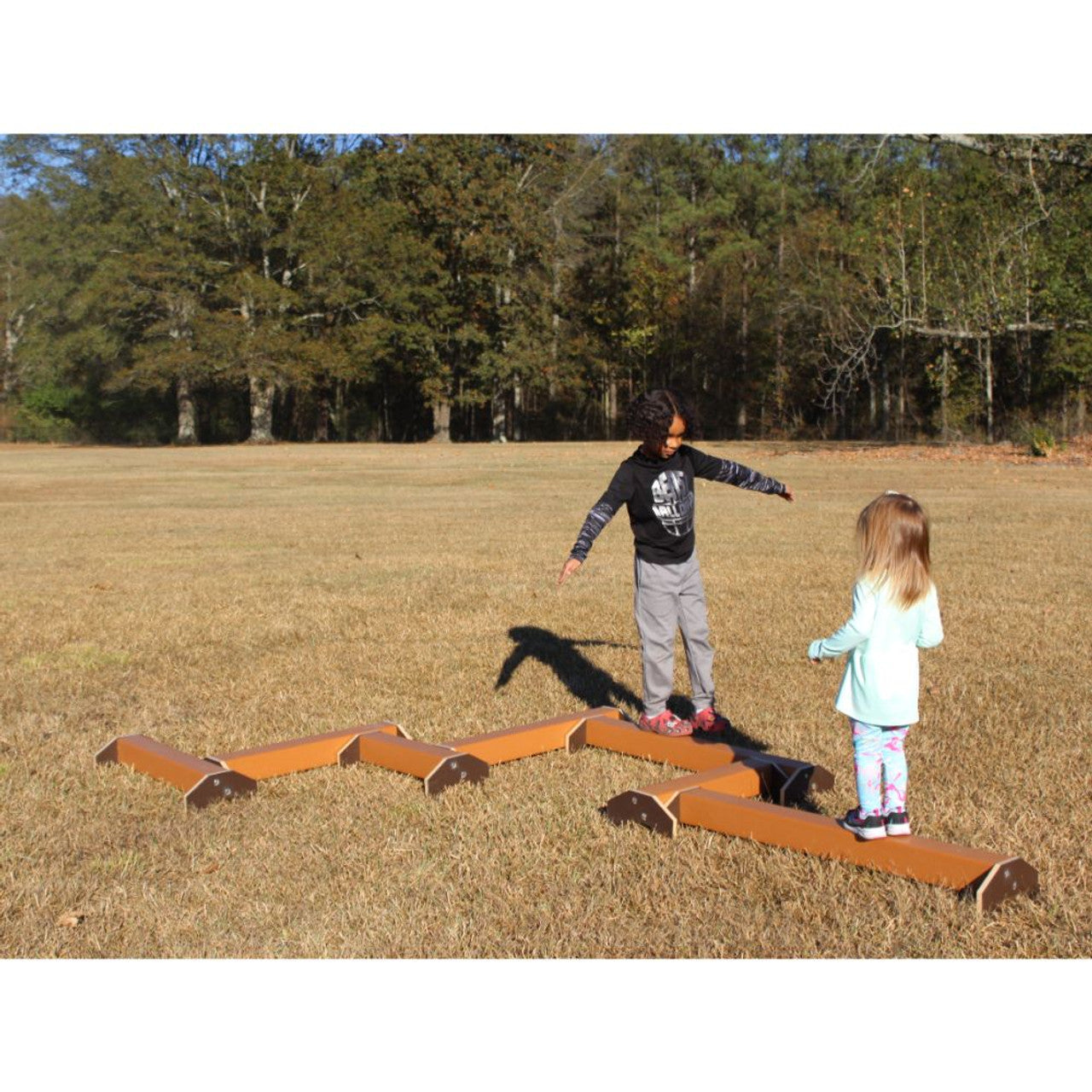 Balance Beam Stackable with seven connected zigzag beams, two children balancing outdoors on grass, promoting coordination and active play