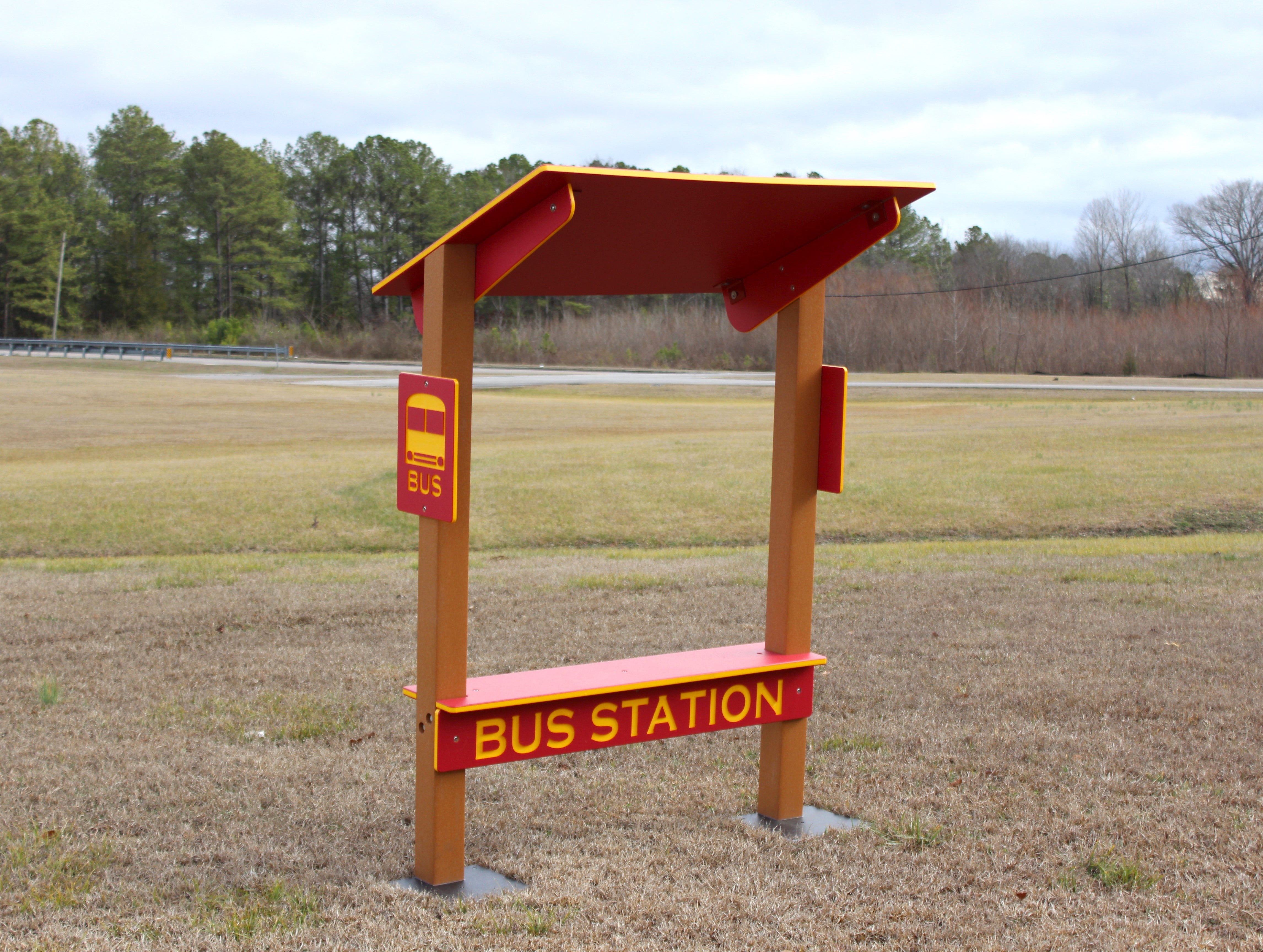 Red and yellow outdoor bus station bench with shaded roof and bus icon panels for playground or school use