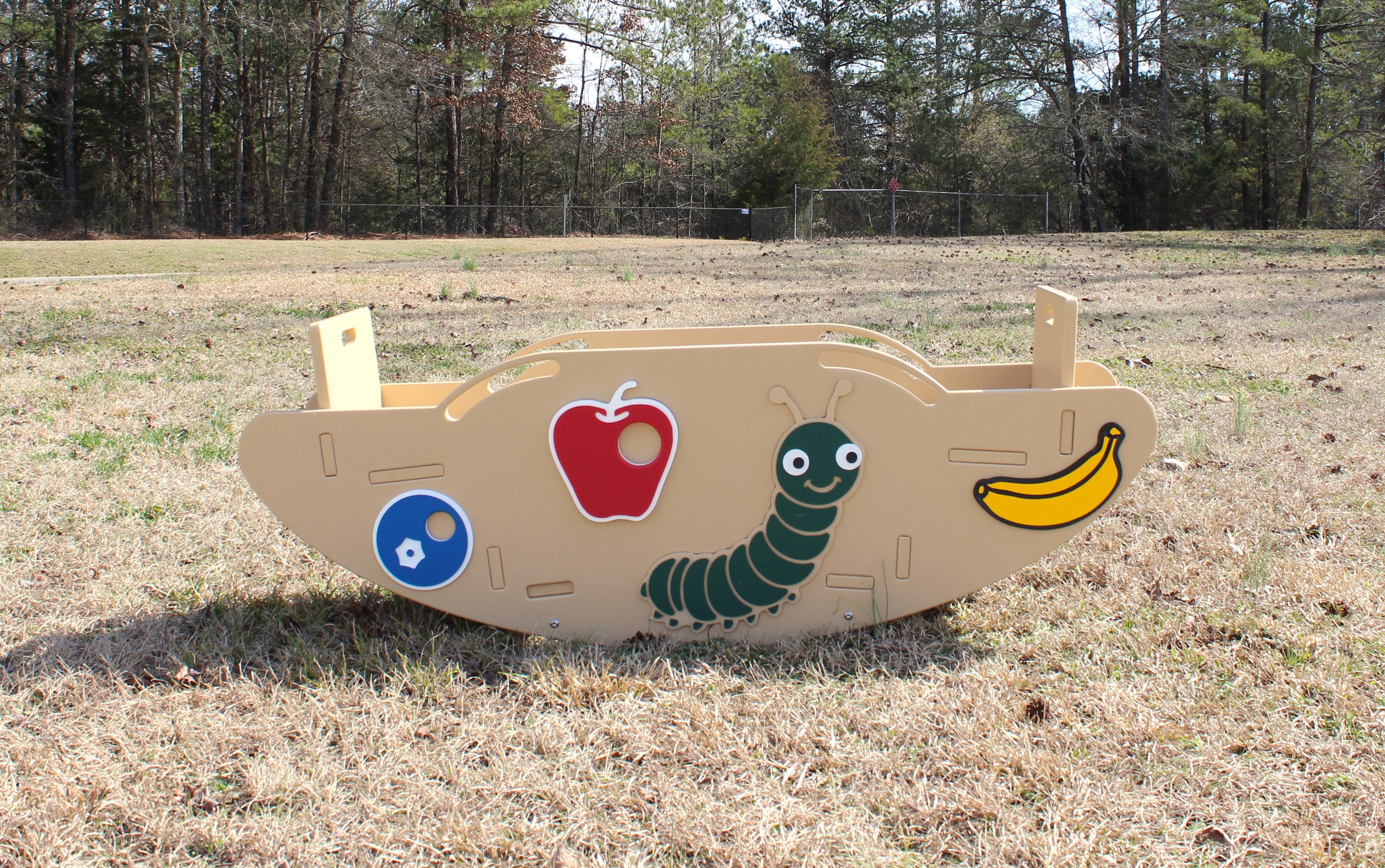 Beige children's seesaw with colorful caterpillar figures, hand holds, and footrests on grassy playground