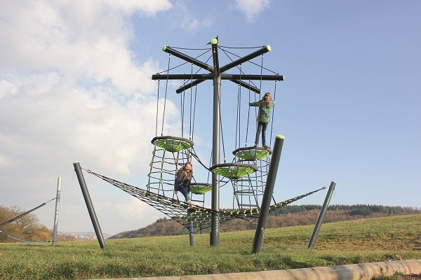 Outdoor climbing structure with four suspended bird's nests, cargo net platform, and climbing nets with children playing