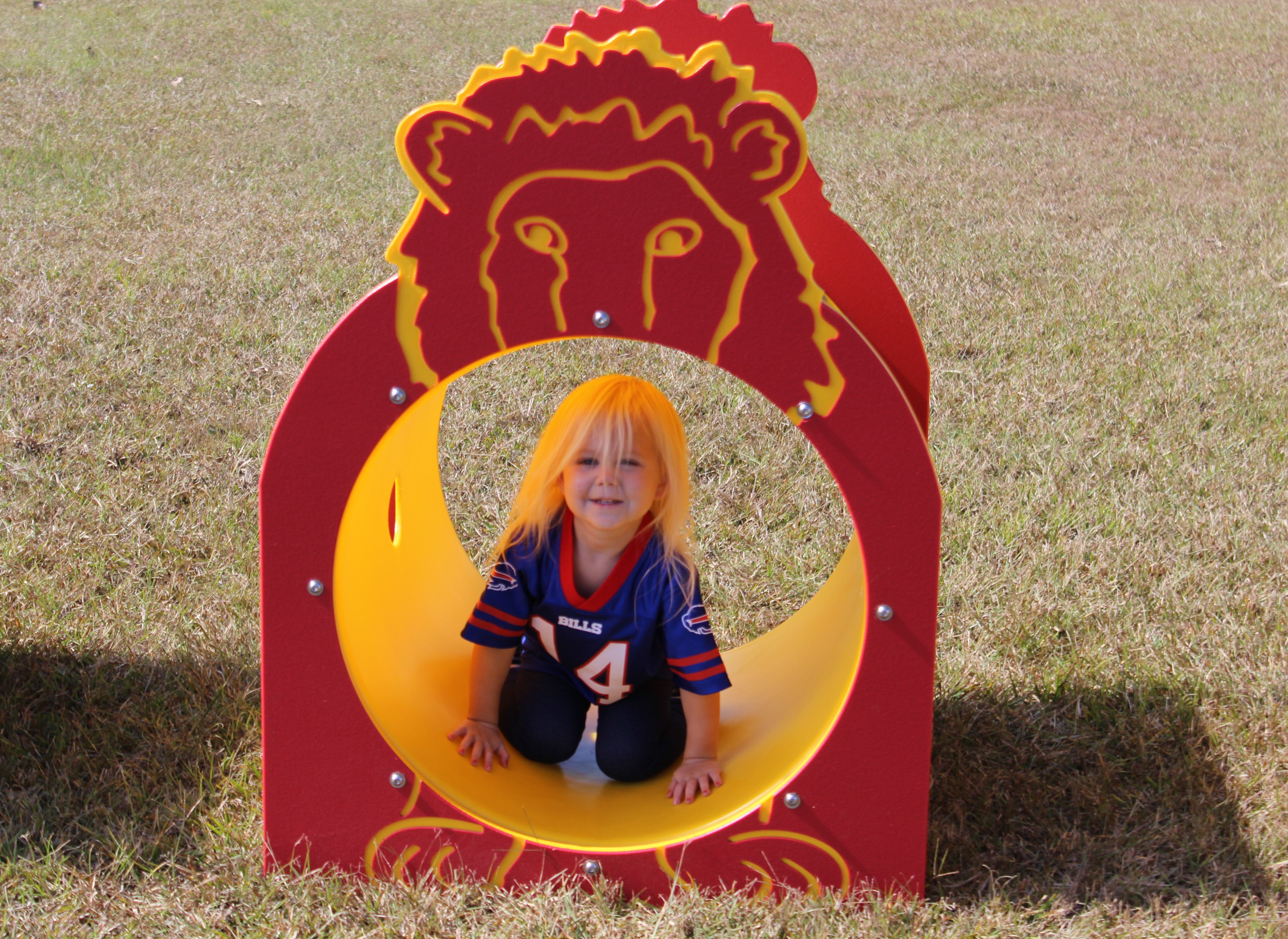Larry The Lion Single Tunnel playground feature with bright red and yellow lion face tunnel and child crawling on grass