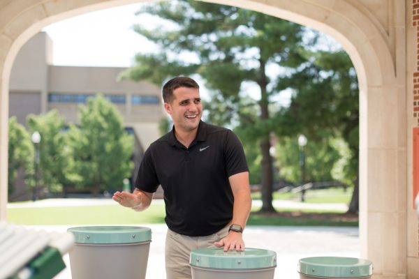Man playing outdoor musical drums from Renaissance Ensemble under stone archway in park setting
