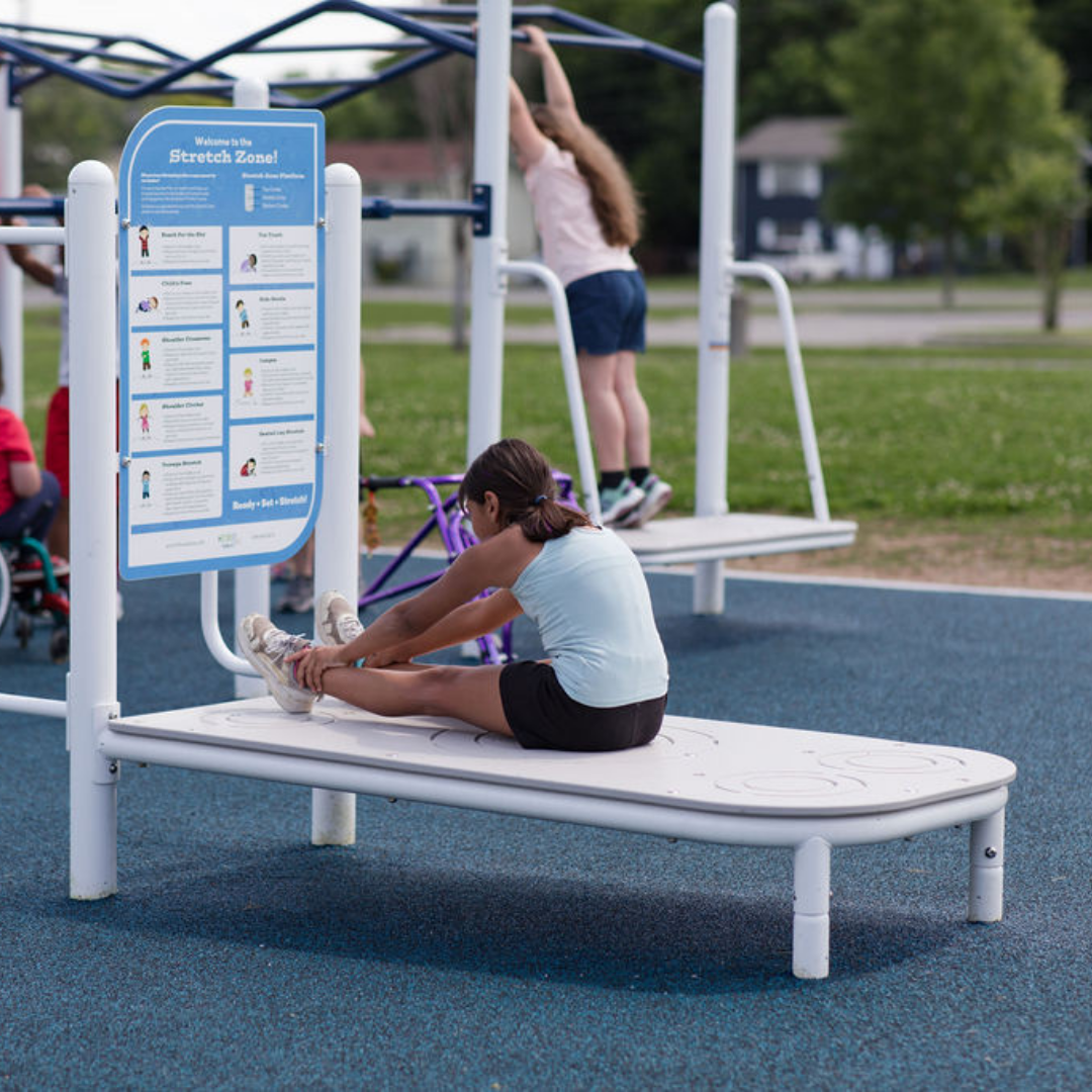 Child stretching on outdoor fitness platform with instructional stretch diagrams and nearby playground equipment