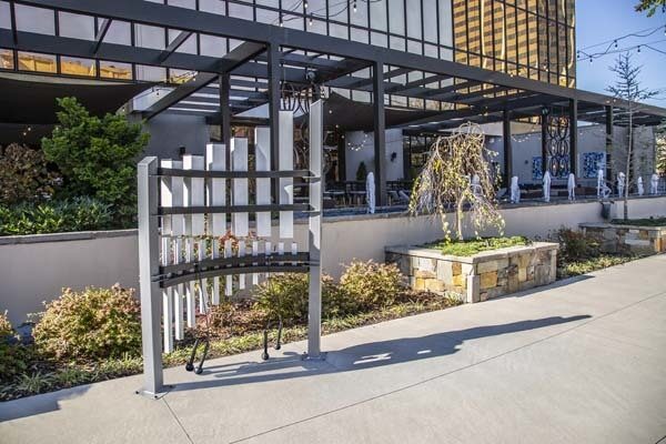 Outdoor musical sculpture with vertical anodized aluminum tubes in a curved modern frame, set in a landscaped urban plaza.
