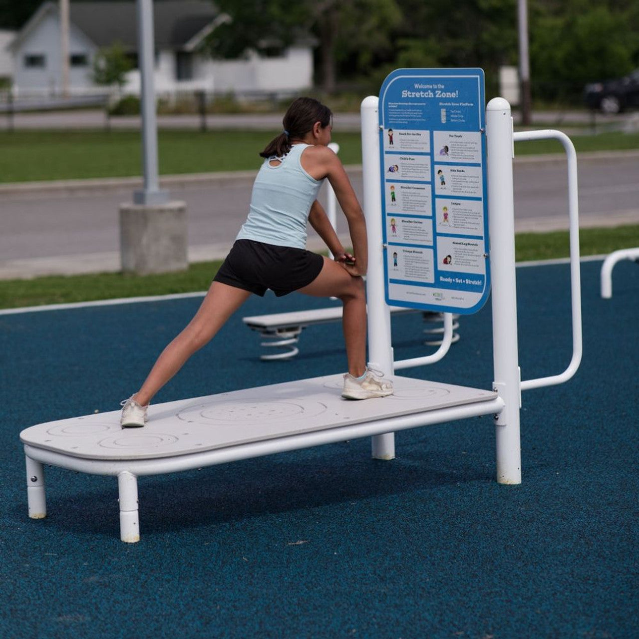 Child using outdoor kids fitness stretch equipment with instructional stretch diagrams on a blue panel