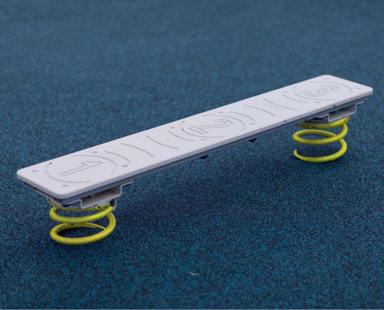 ActionFit Kids Balance Zone outdoor workout equipment with white balance board, yellow coil springs, and blue safety surface