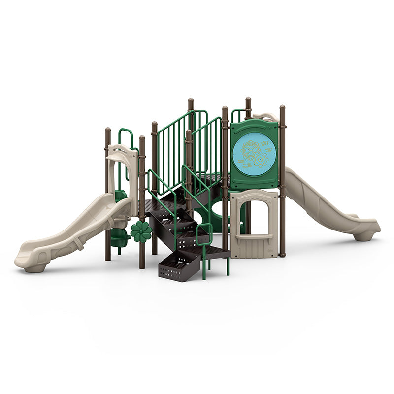 Outdoor playground structure with two beige slides, green railings, climbing stairs, and interactive play panels.