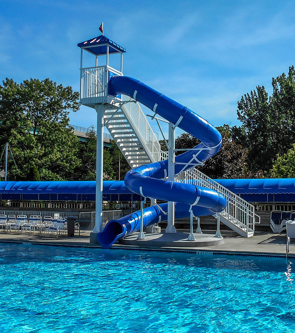 Blue spiral water slide with open white stairs and platform beside a clear swimming pool under a bright sky