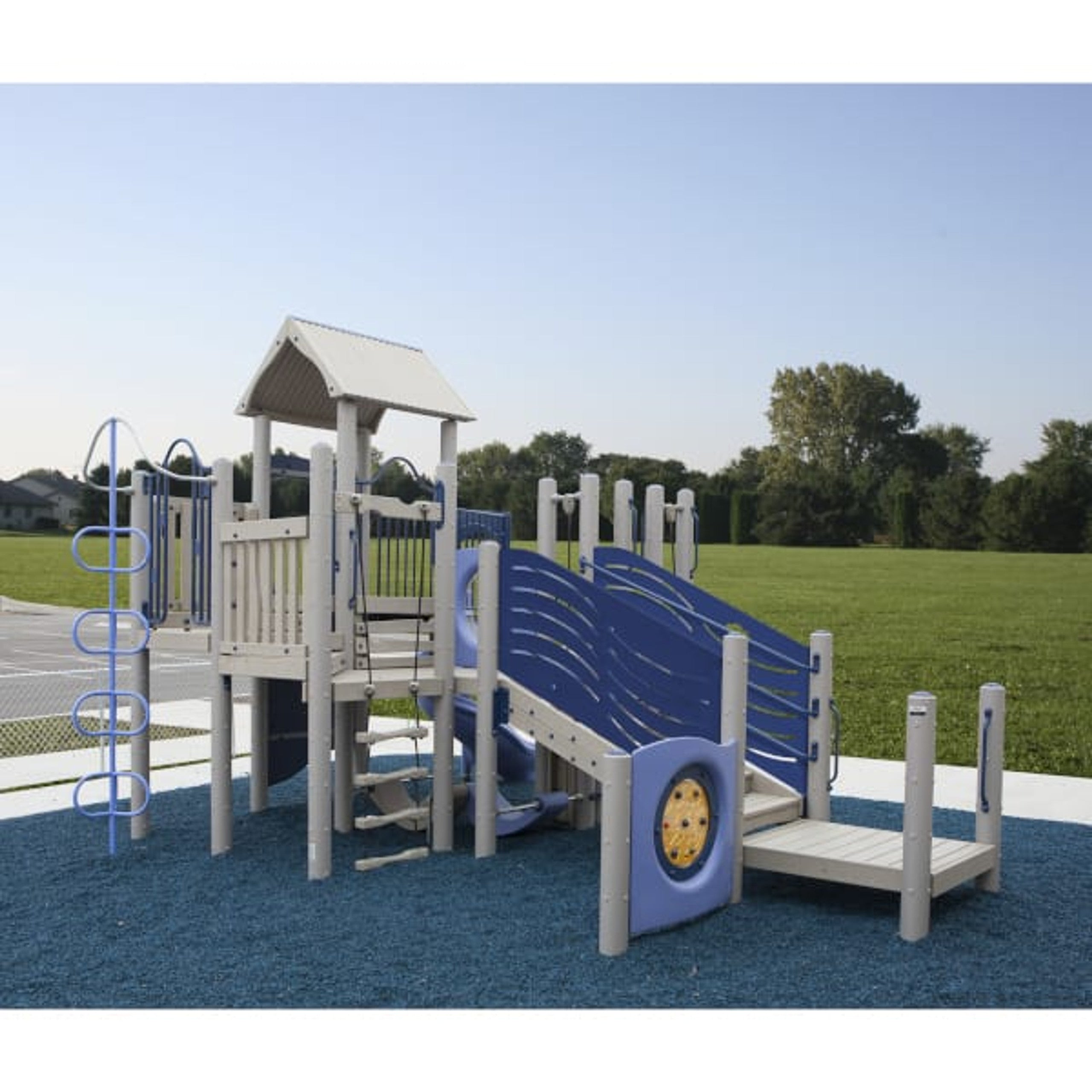 Outdoor playground structure with spiral slide, climbing wall, rope ladder, and blue safety surfacing