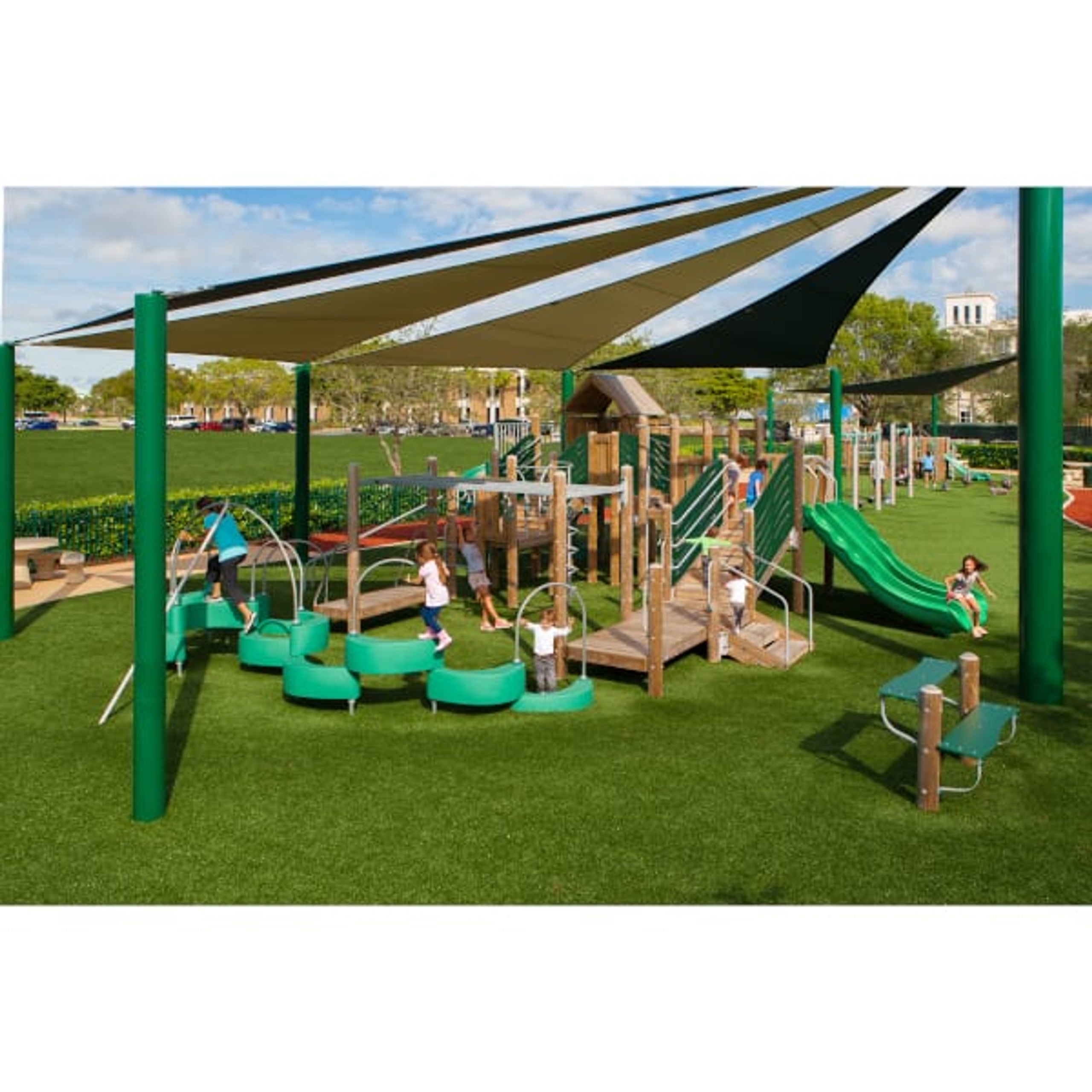 Outdoor playground with triple wave and spiral slides, climbing net, shaded canopies, and children on artificial turf