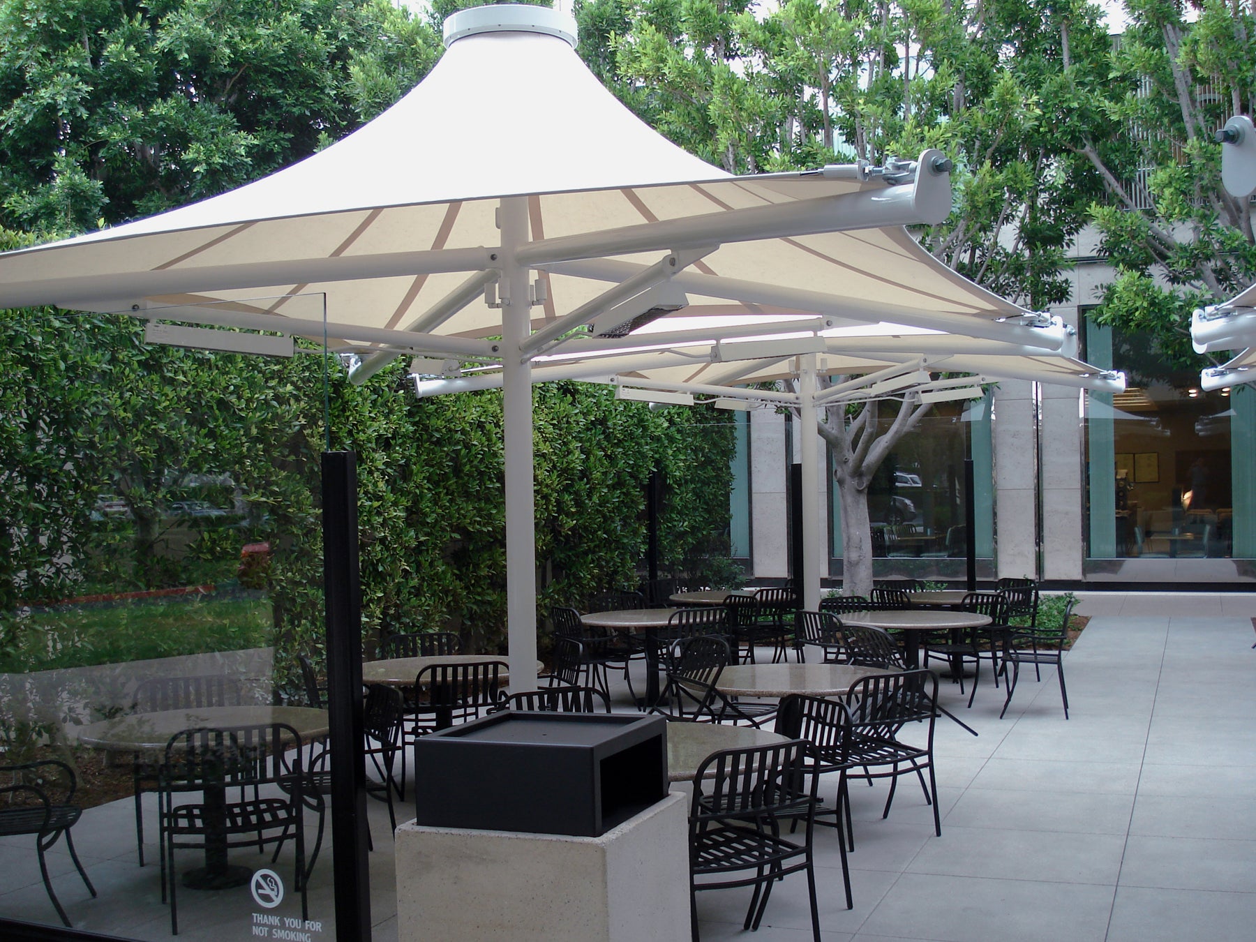 Twilite 4 Point Shade Structure with single-column design and contoured white fabric roof over outdoor seating area