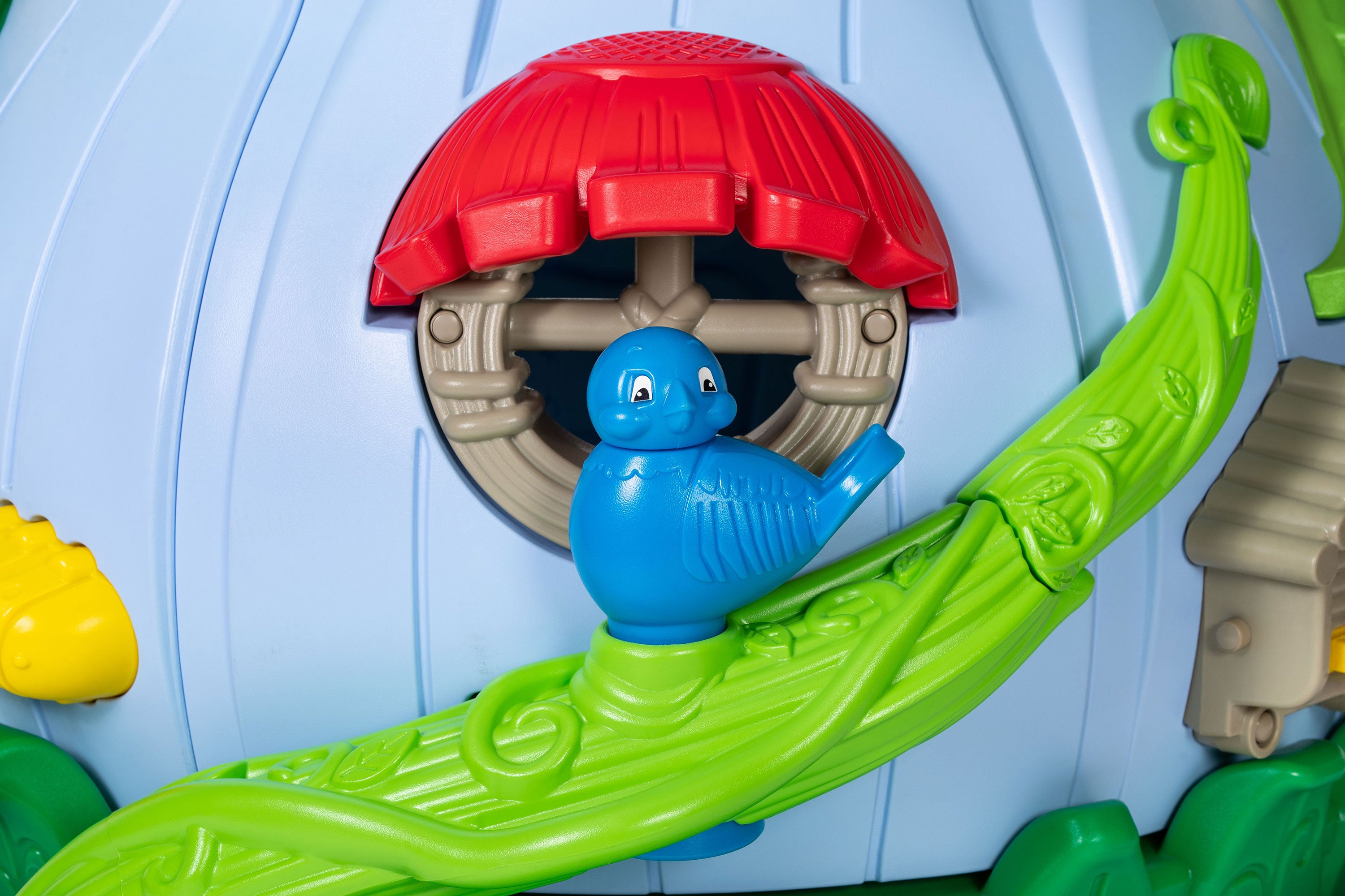 Nature-themed preschool playground panel with blue bird on green vine and red awning window; toddler play system detail