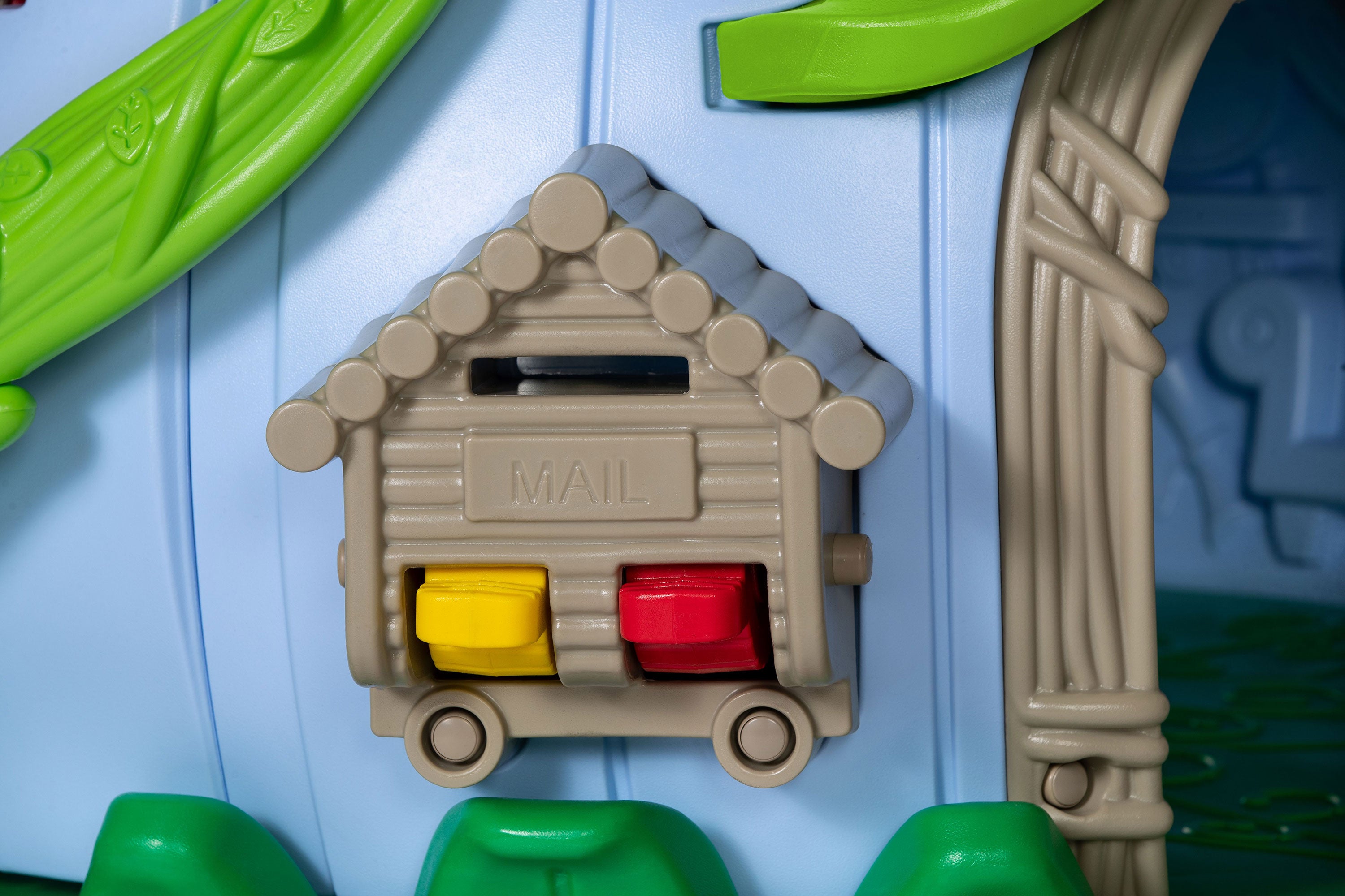 Toddler playground mailbox panel with yellow and red block sliders on a blue wall, leaf and vine accents for sensory play.