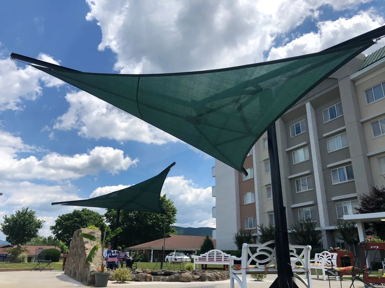 Rotating Shade Sail Structure with green triangular shade sails and black powder-coated steel posts in outdoor seating area