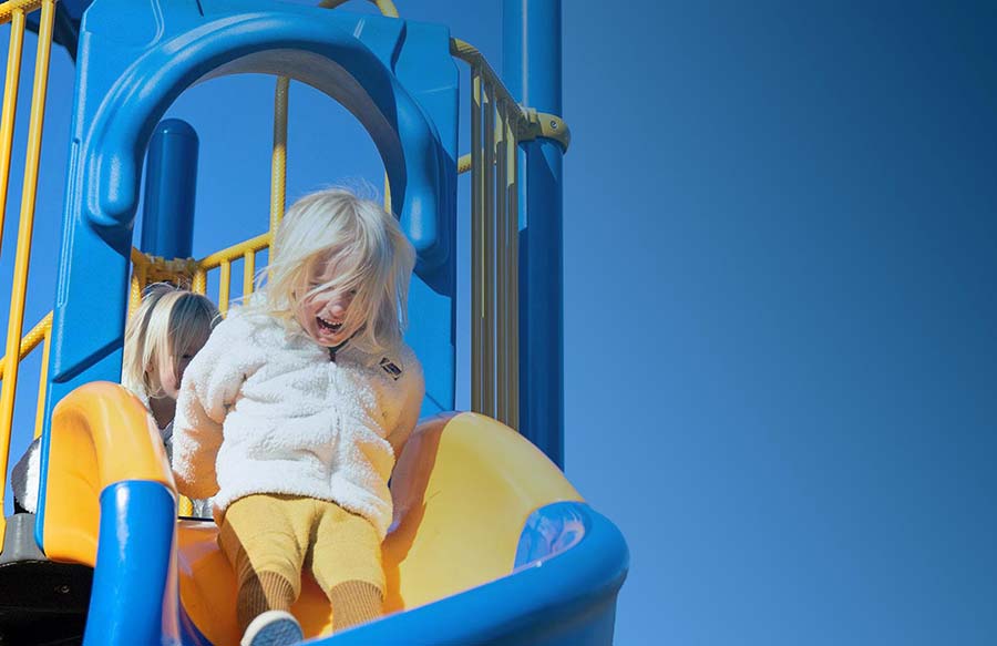 Playground Equipment. Girl Sliding down a slide at a park