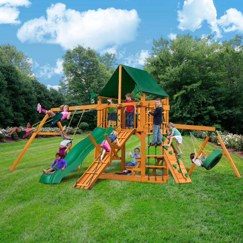 Cedar wooden playset with green canopy, Alpine Wave slide, climbing ramp, rock wall, tire swing, and children playing outdoors
