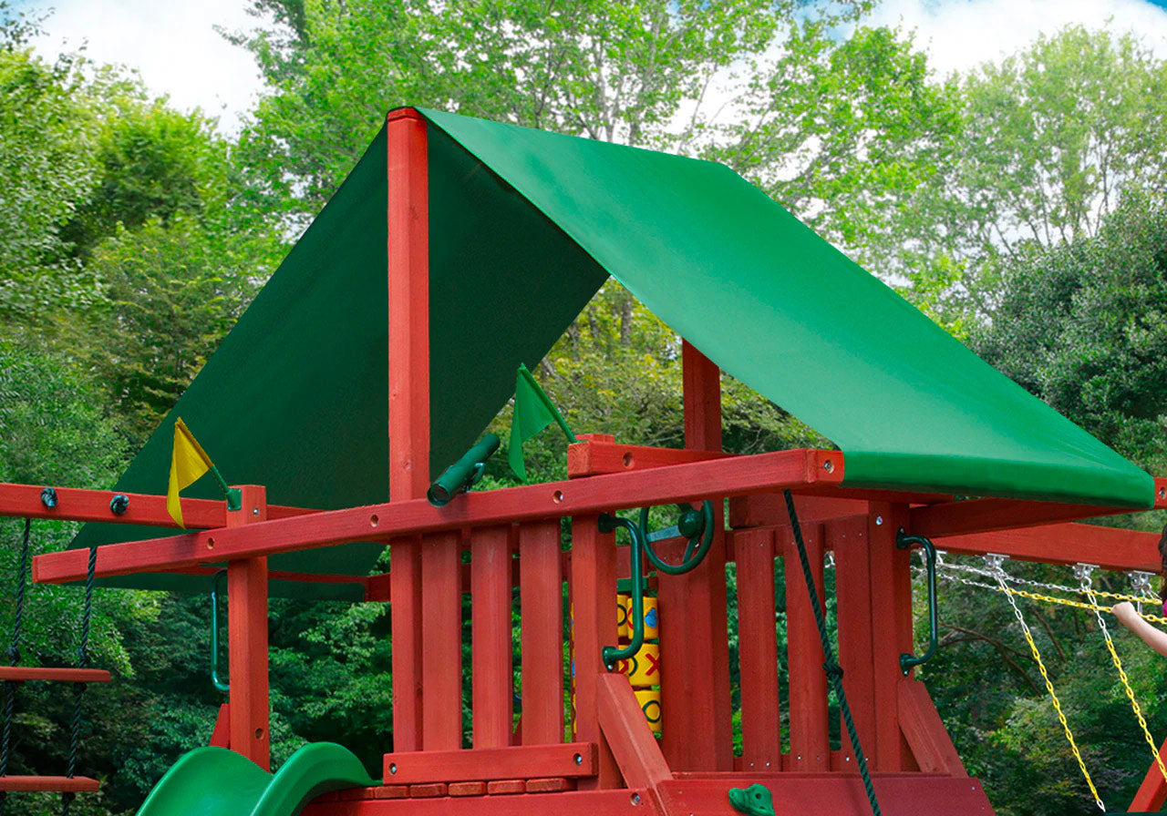 Redwood swing set with green vinyl canopy, tic-tac-toe panel, steering wheel, and multiple swings in backyard setting