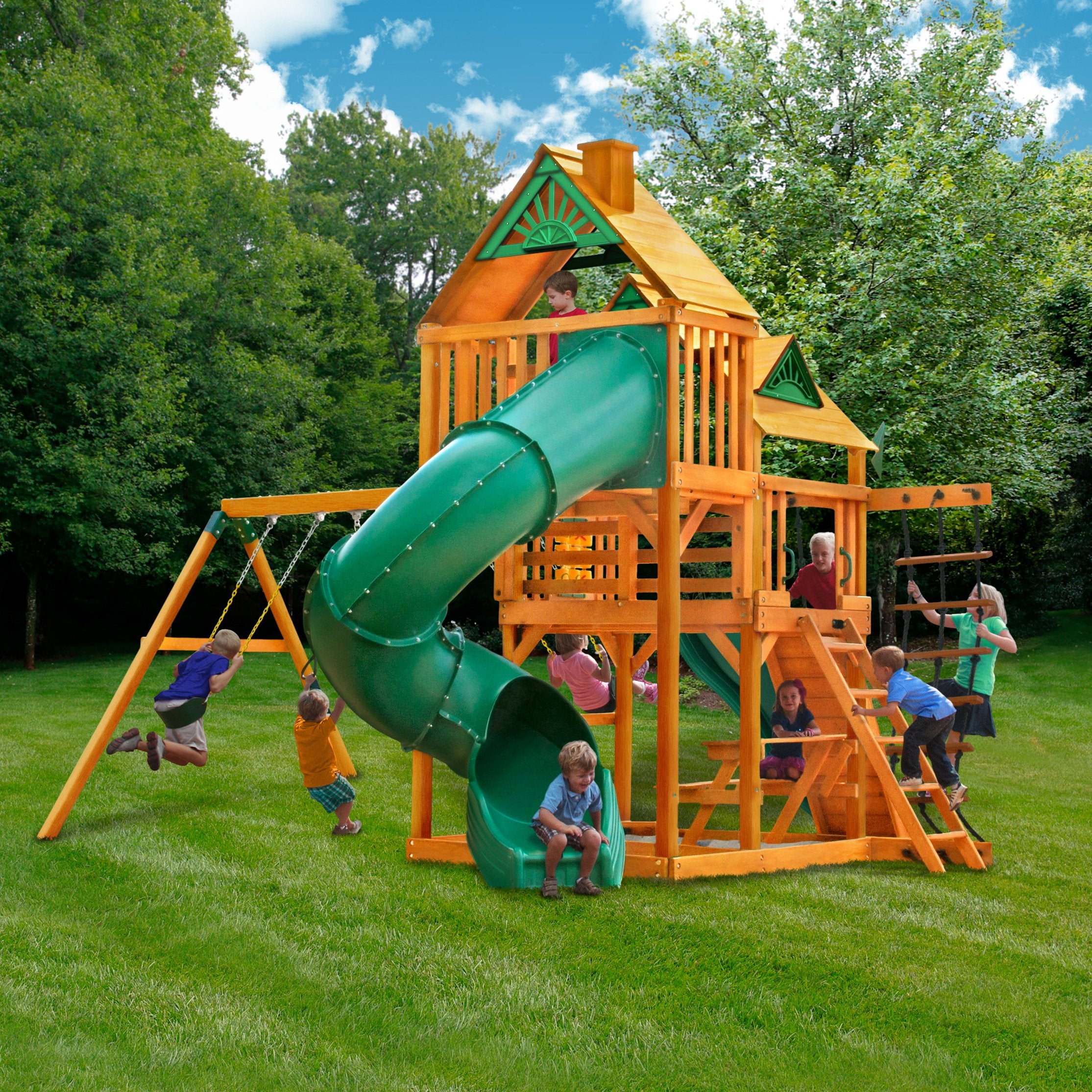 Cedar wooden playset with green spiral slide, dual swings, climbing ladder, picnic table, and children playing outdoors