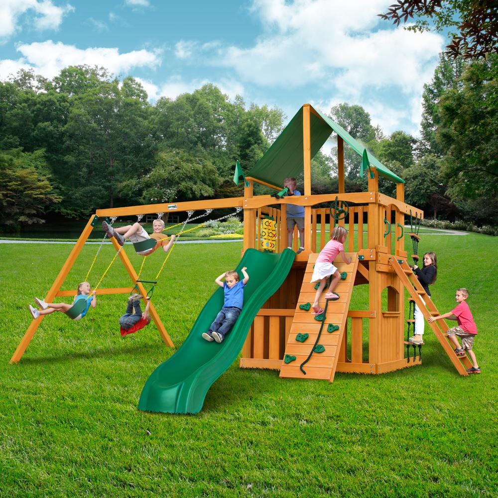 Wooden playset with green vinyl canopy, green slide, swings, climbing wall, tic-tac-toe panel, and children playing