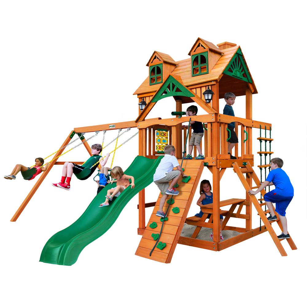 Wooden playset with green wave slide, rock climbing wall, swings, tic-tac-toe panel, and built-in picnic table with children playing