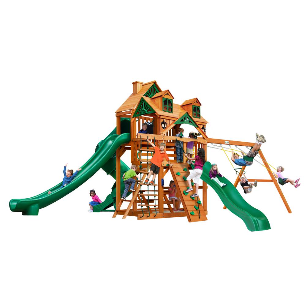 Cedar wooden playset with green slides, swings, climbing walls, and children playing on multiple levels
