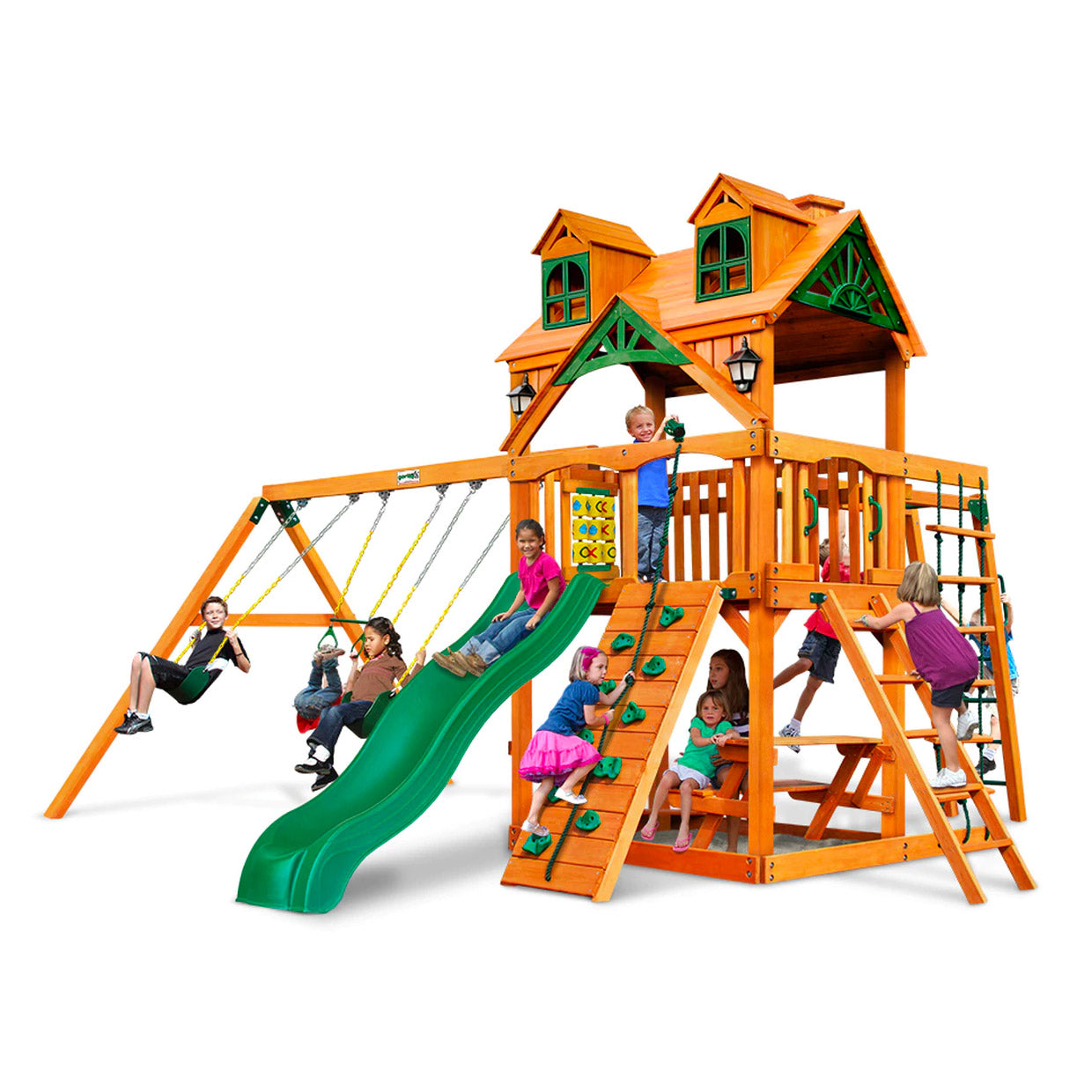 Amber-finished wooden playset with green slide, swings, climbing walls, rope ladder, picnic table, and playhouse roof with dormer windows