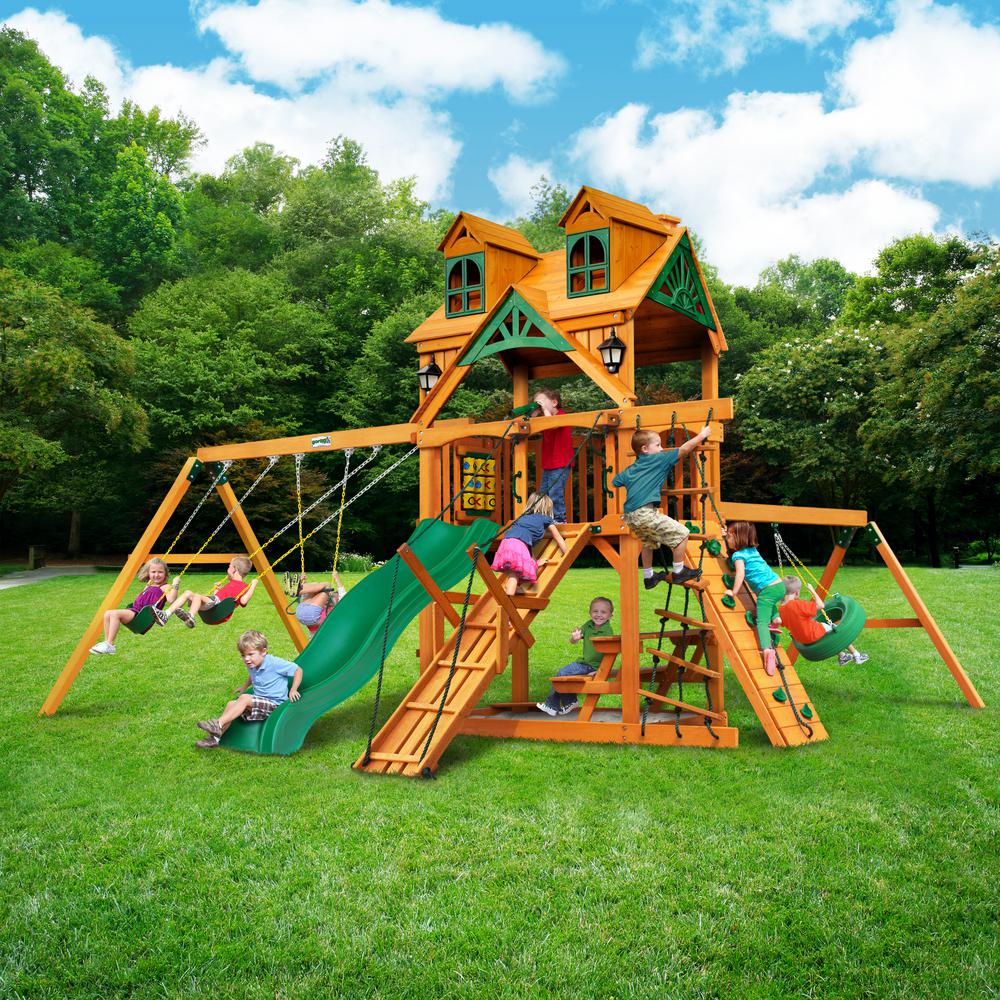 Cedar wooden playset with Malibu wood roof, green slide, swings, climbing walls, and children playing outdoors