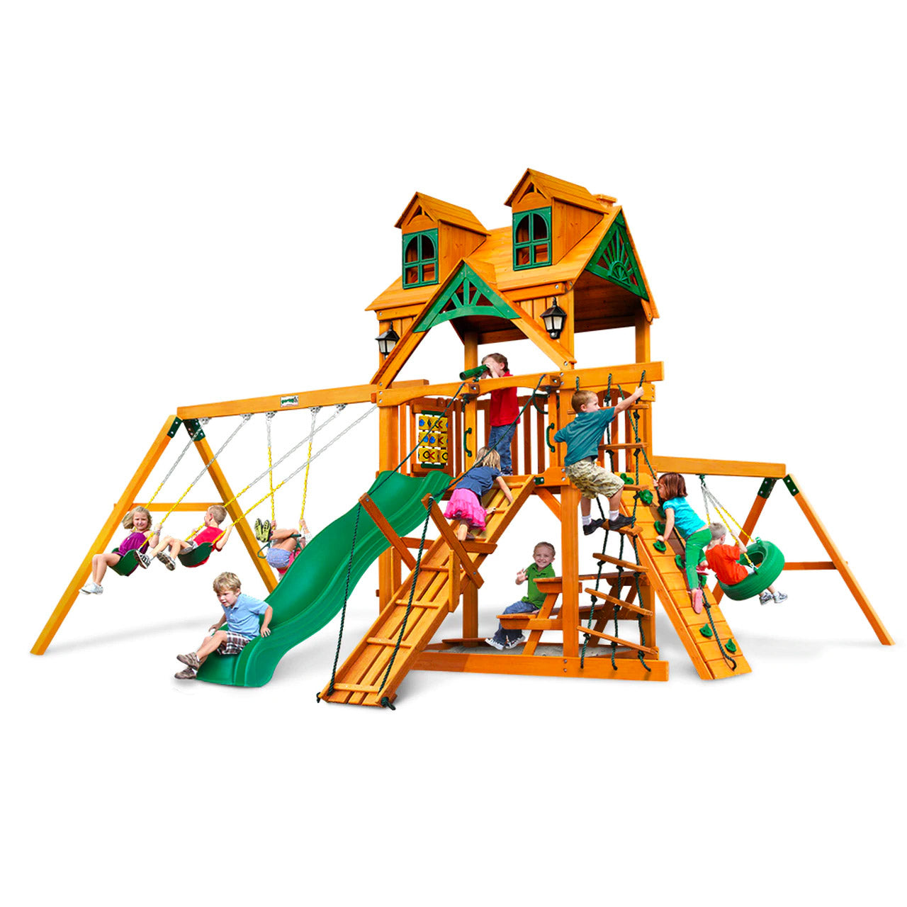 Cedar wooden playset with green slide, swings, climbing ramps, tire swing, and children playing on various features