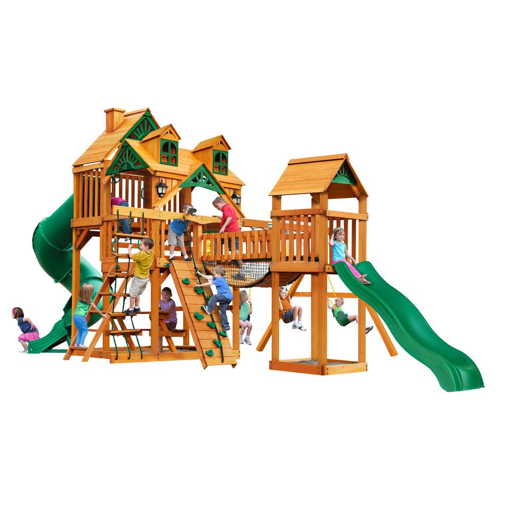 Cedar wooden playset with green slides, climbing walls, rope ladder, swings, and children playing outdoors