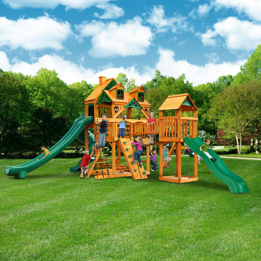 Wooden playset with Malibu wood roof, green slides, climbing wall, rope ladder, swings, and children playing outdoors