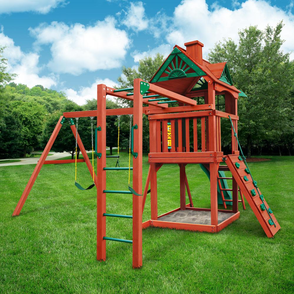 Cedar wood playset with redwood stain featuring swings, climbing wall, sandbox, and elevated clubhouse with decorative roof.