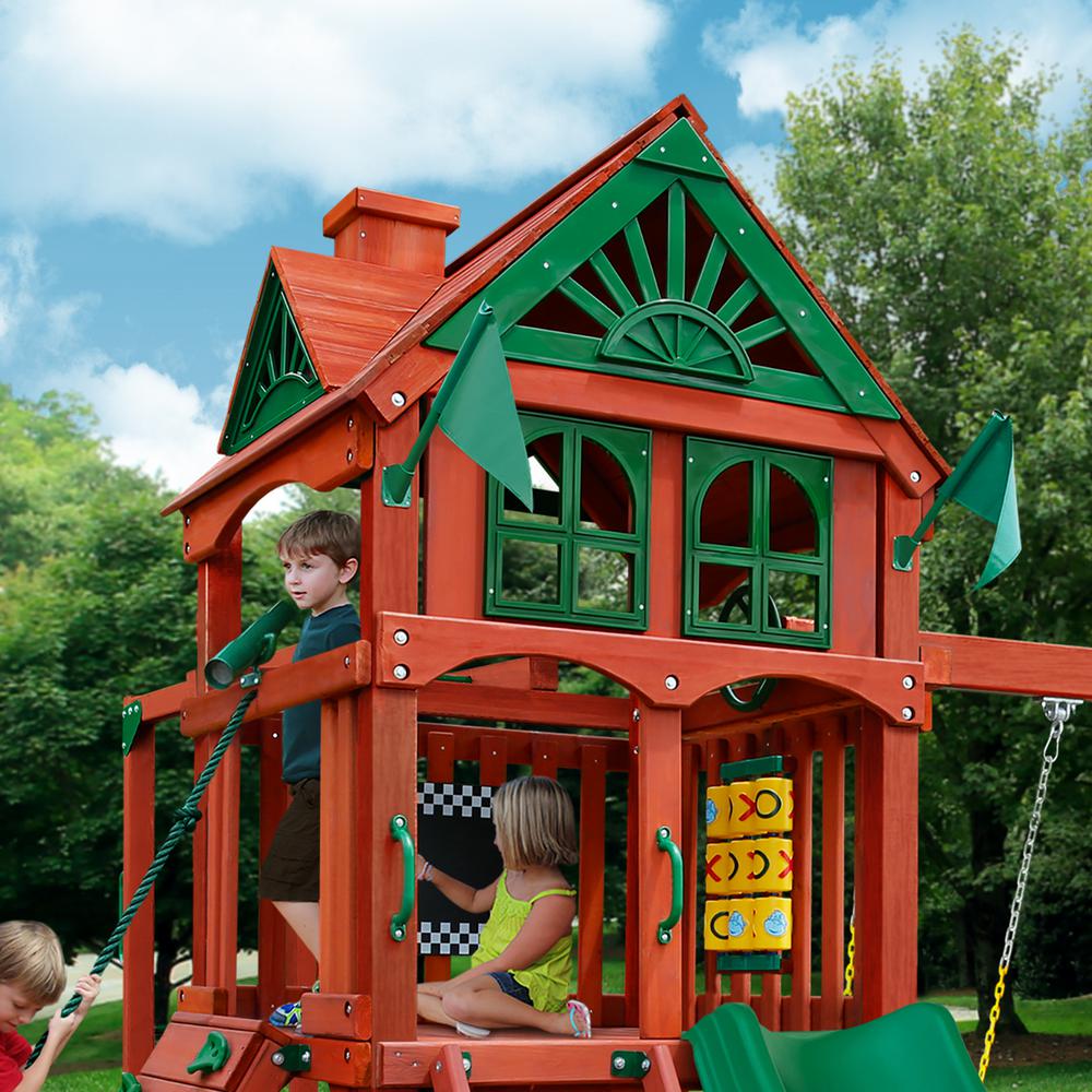 Cedar wooden playset with green accents, clubhouse with decorative windows, tic-tac-toe panel, climbing rope, and slide with children playing
