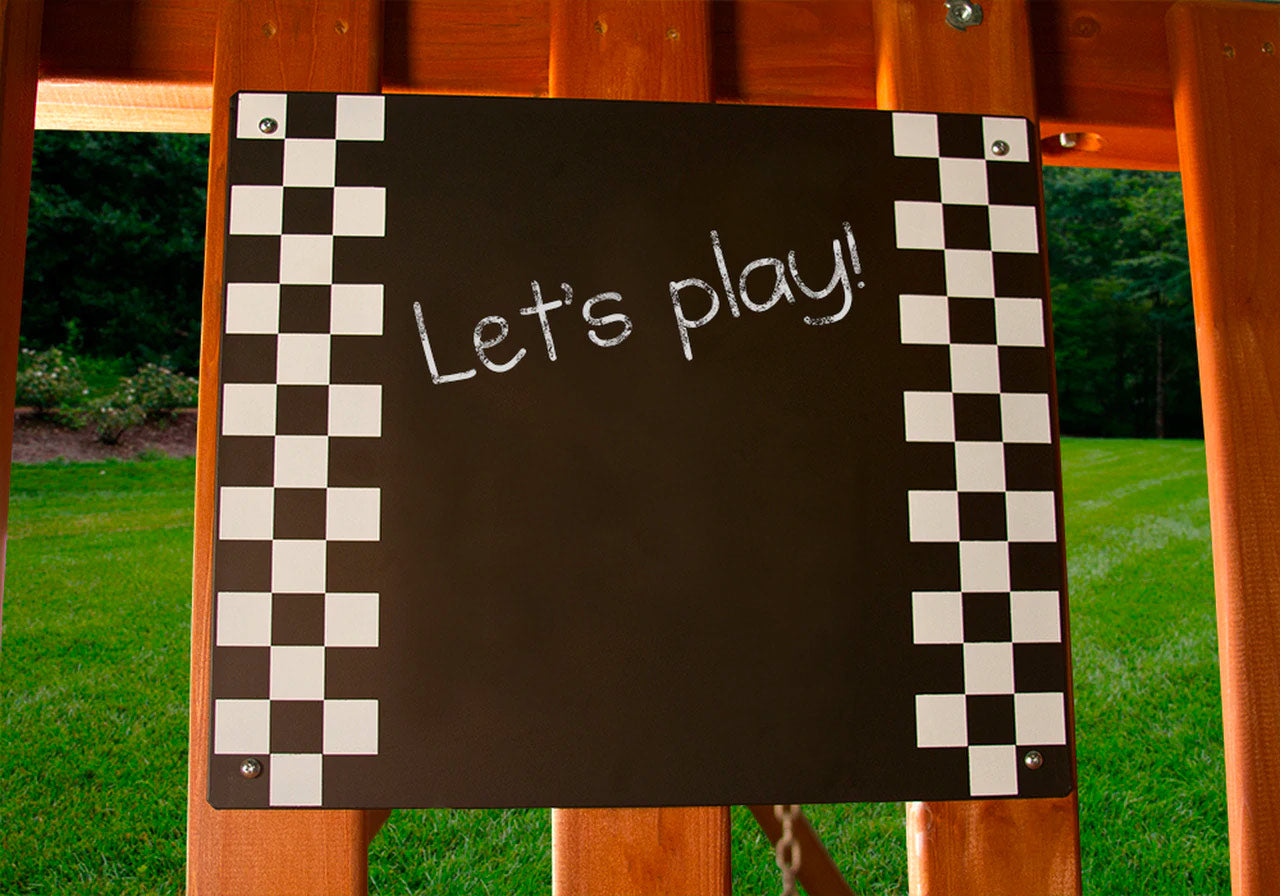 Chalkboard panel with checkerboard border mounted on cedar wood playset in outdoor grassy area