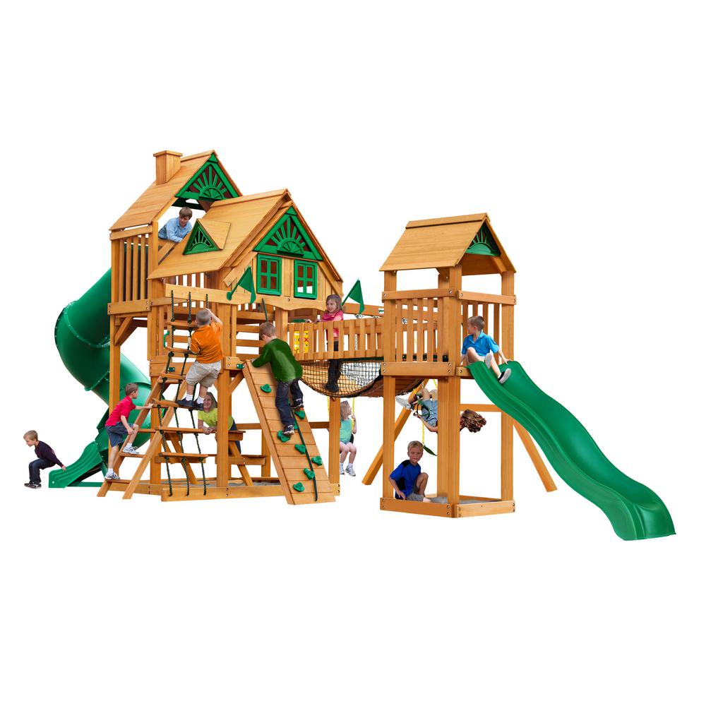 Cedar wooden playset with green slides, climbing walls, rope ladders, and children playing on various features