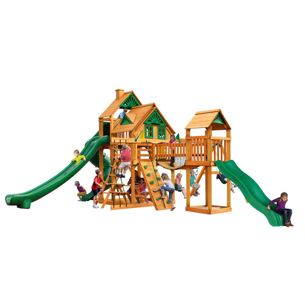 Wooden playset with two green slides, climbing walls, rope ladder, swings, and children playing outdoors