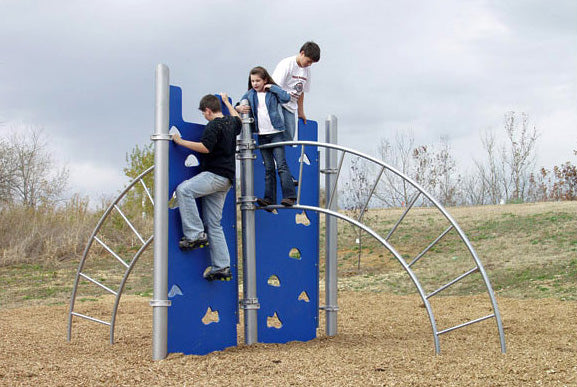 Children climbing on blue dual climbing walls with metal sideways ladders on outdoor playground mulch surface