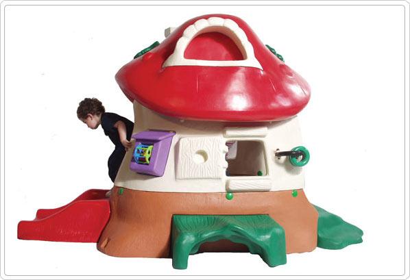 Colorful mushroom-shaped toddler playhouse with slide, activity panels, small green bench, and whimsical Toad Stool chair for outdoor play.