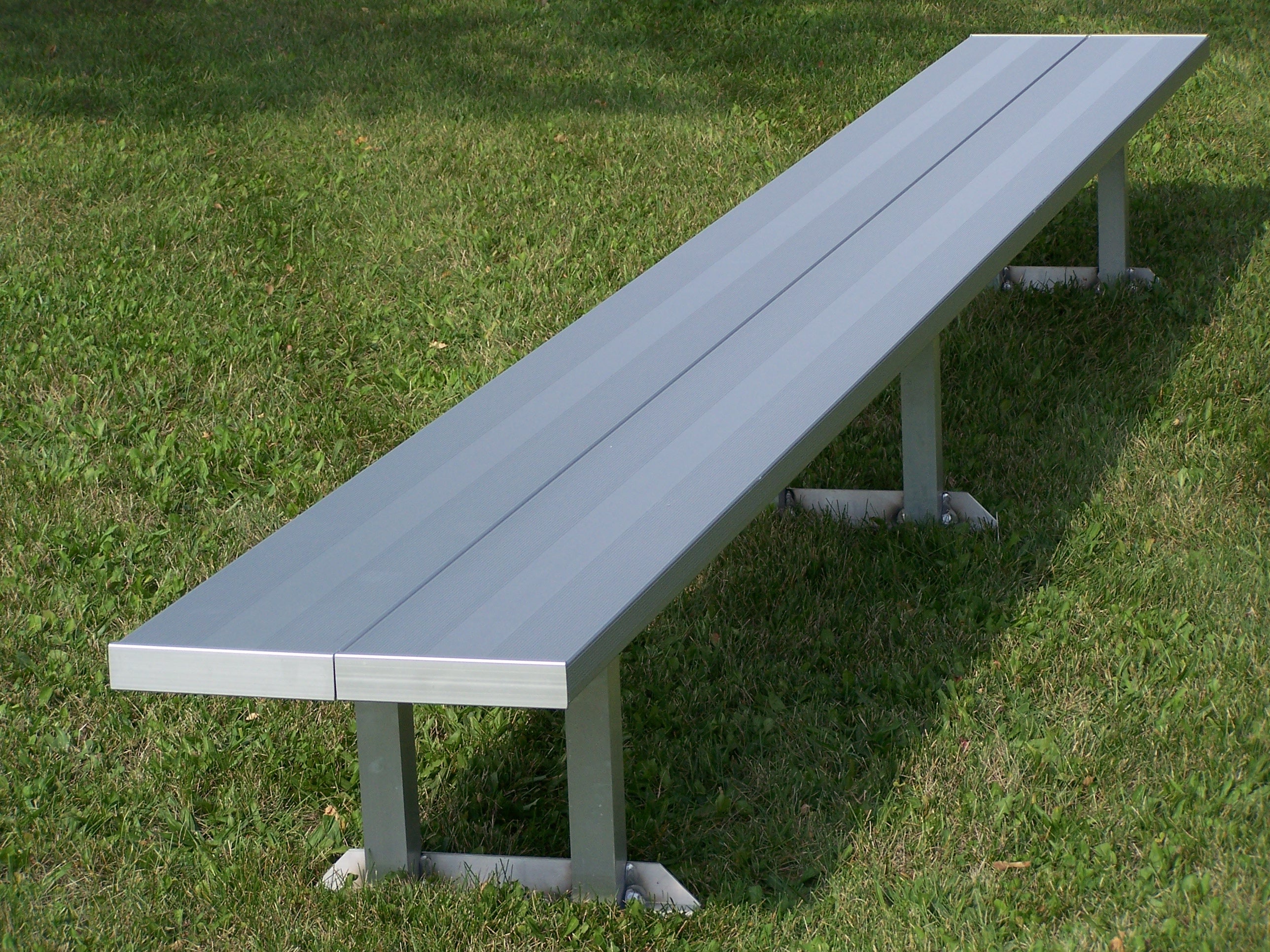 Aluminum portable double wide bench with anodized seat planks and metal legs on grass